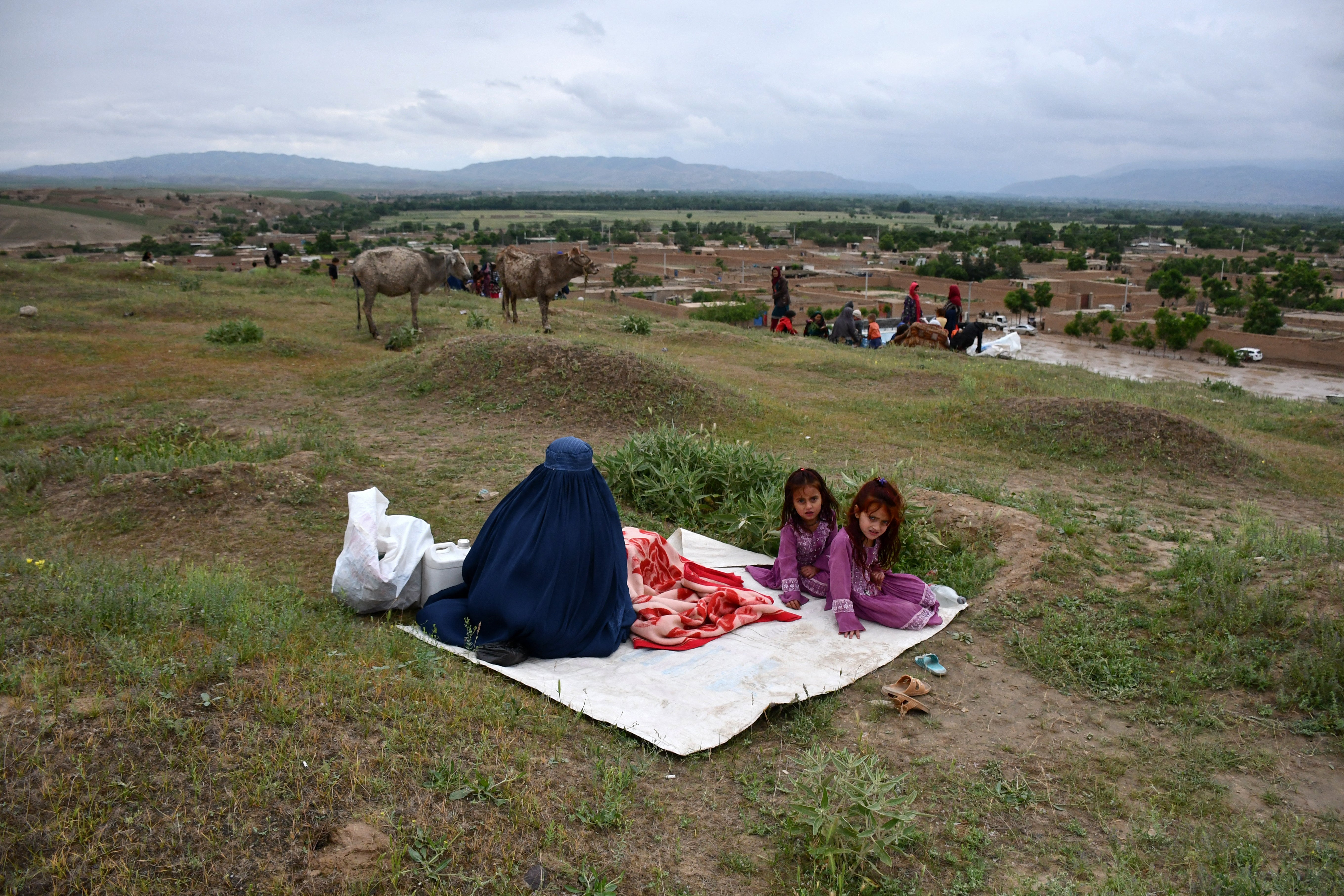 Afghan residents whose houses are swamped with mud gather on a hillside following flash floods after heavy rainfall at a village in the Baghlan-e-Markazi district of Baghlan province