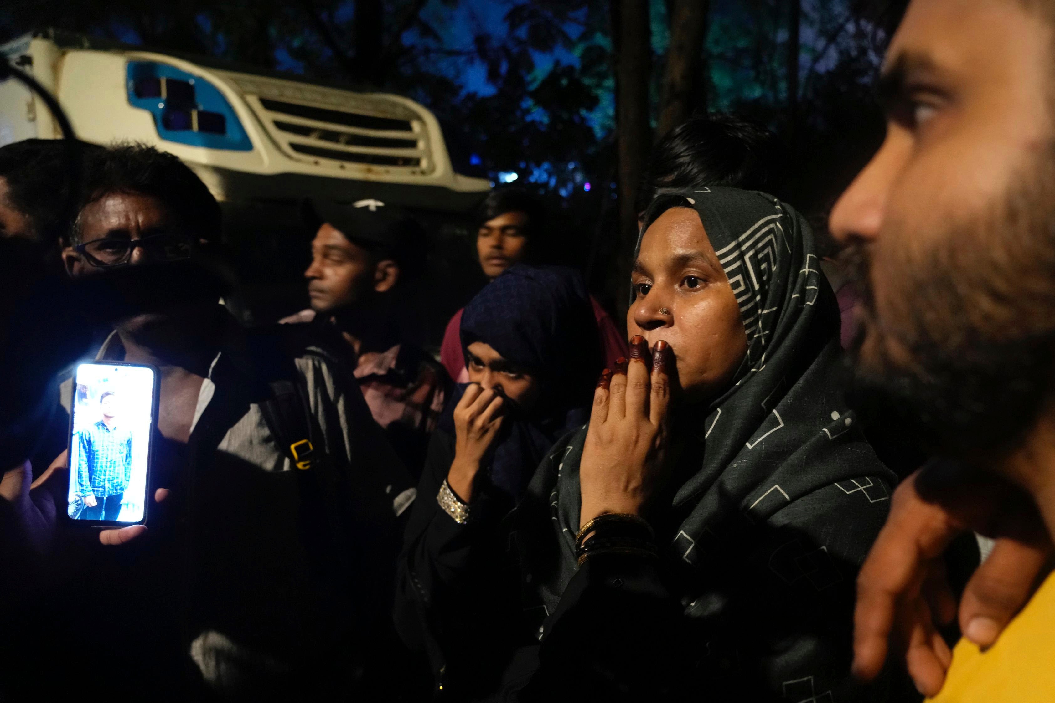 People look for their missing relatives at the site of a collapsed billboard