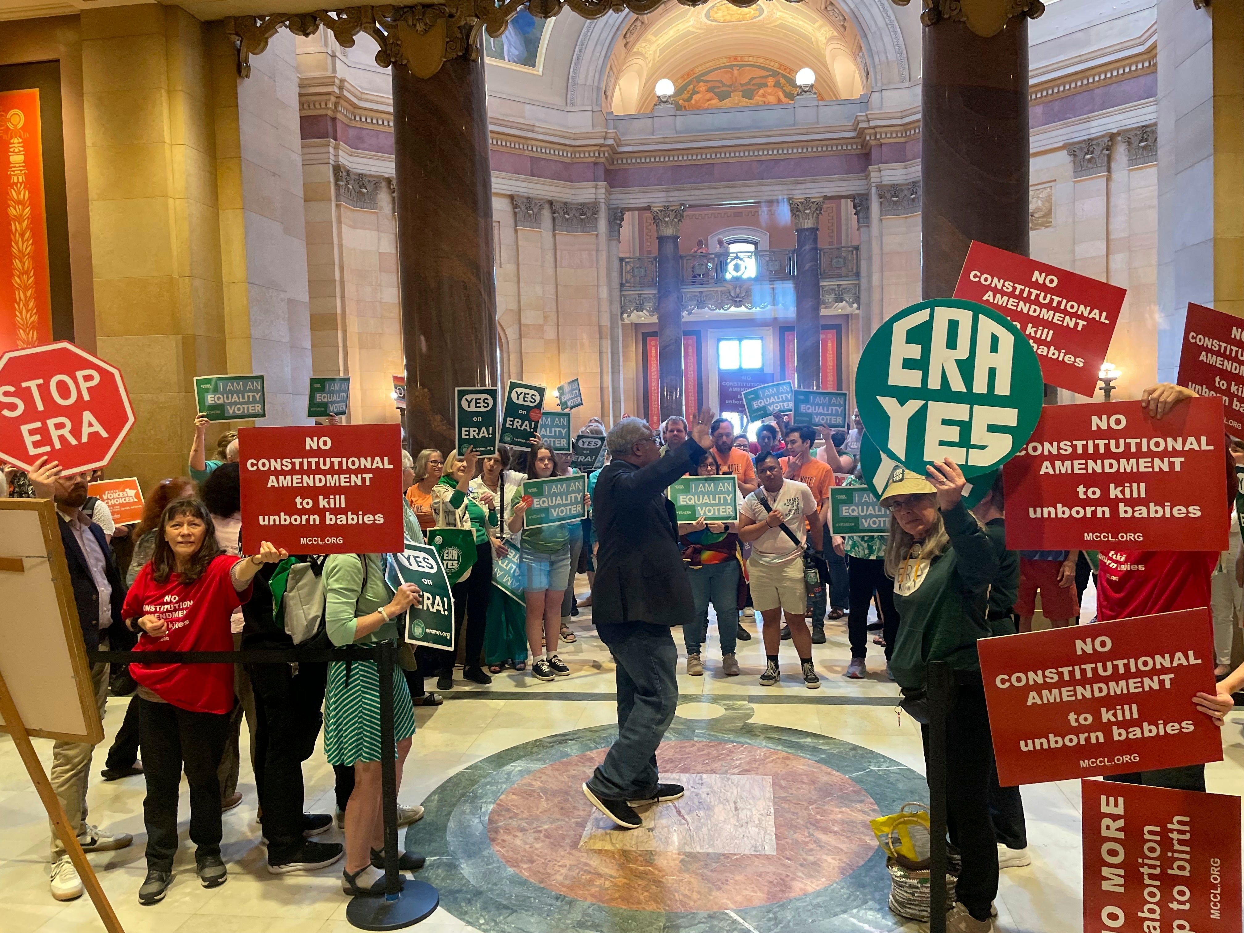 Dozens of supporters and opponents of the Minnesota Equal Rights Amendment legislation hold signs at a rally