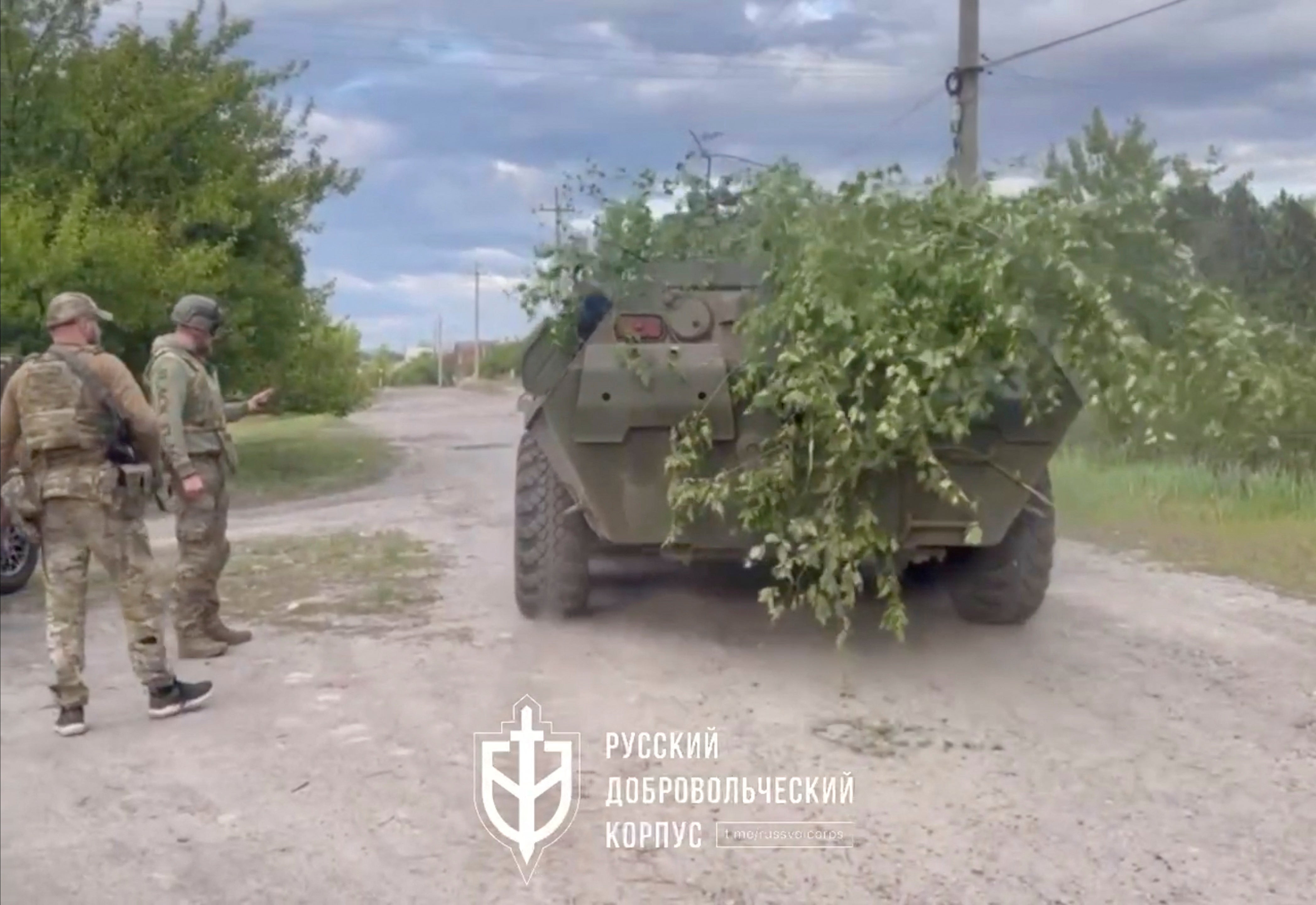 Fighters with the Russian forces stand next to an armoured vehicle in Vovchansk, Kharkiv Oblast