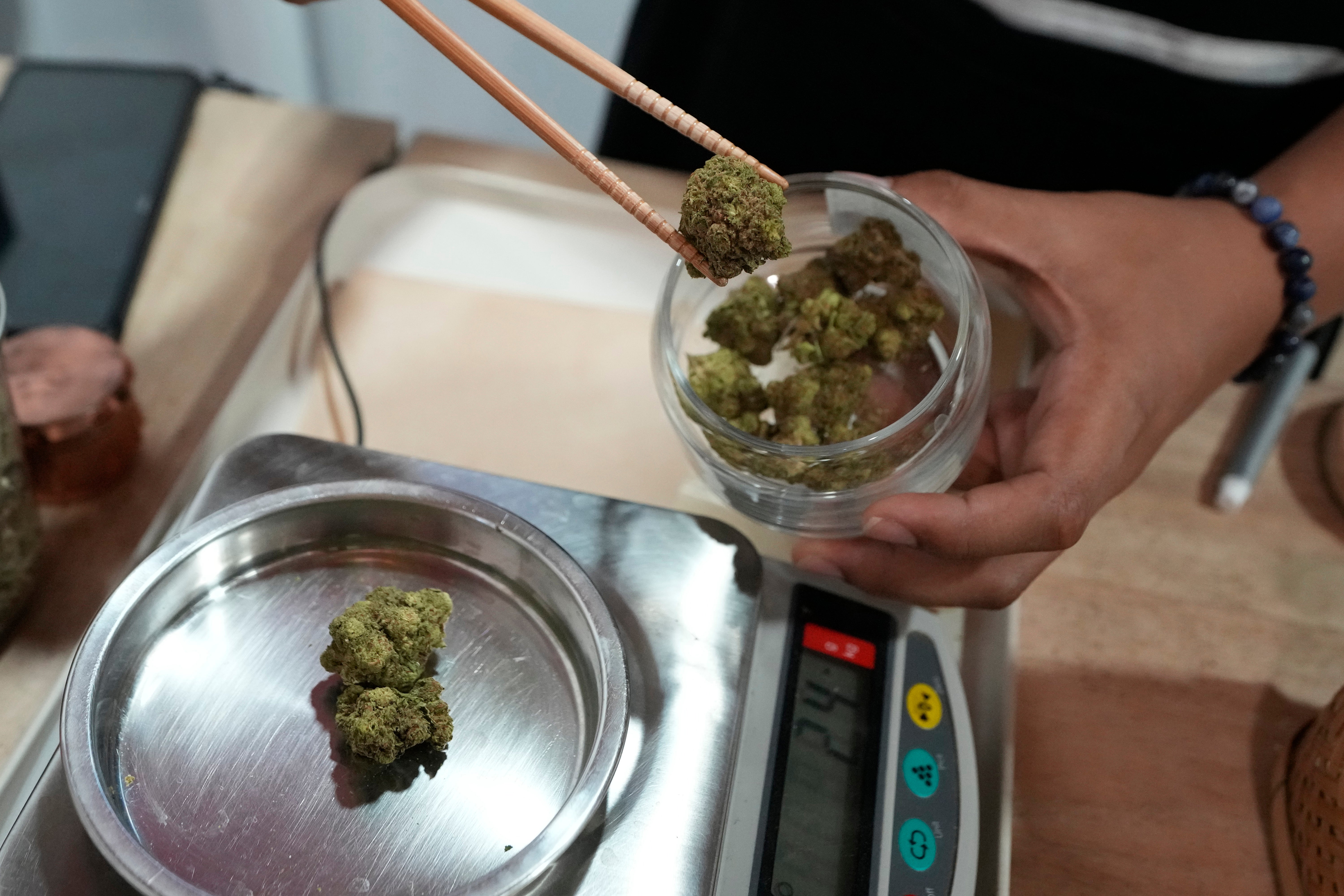 A worker prepares a flower bud of marijuana for a customer at a cannabis shop in Bangkok