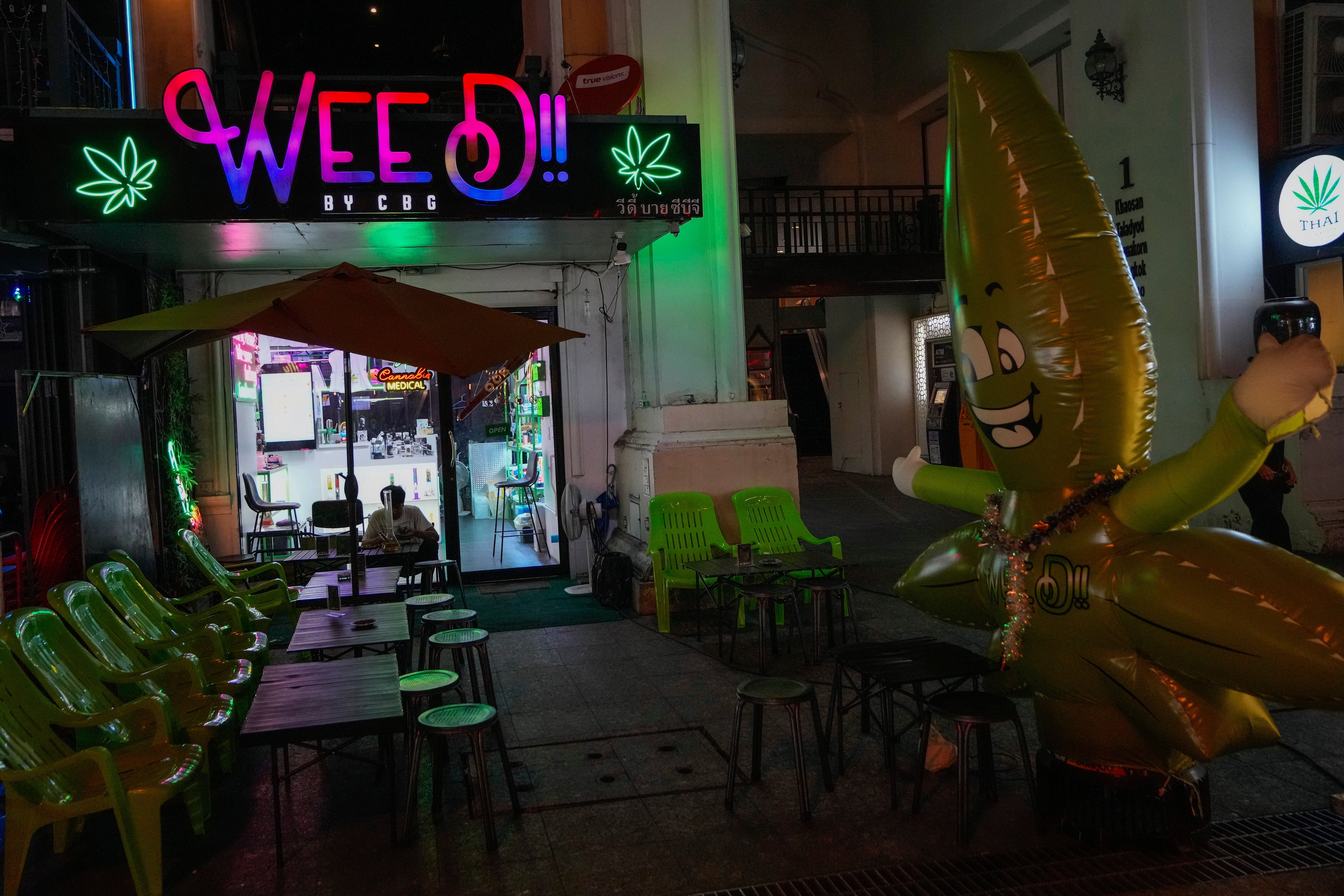 A tourist sits outside a cannabis shop in Bangkok, Thailand