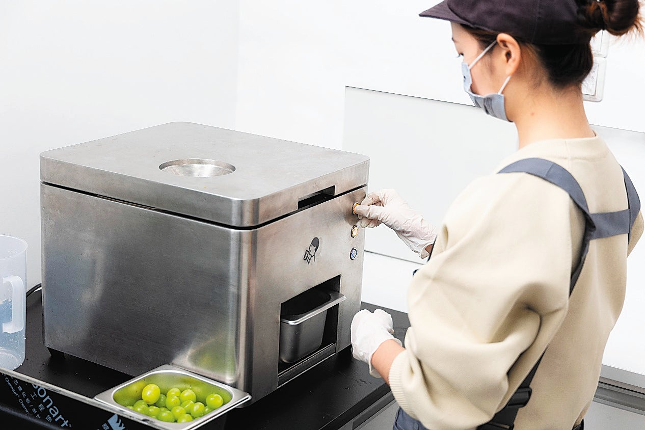 A Heytea employee uses an automated peeling machine to get the raw material for its green grape milk tea during the 4th China International Consumer Products Expo in Haikou, Hainan province, in April