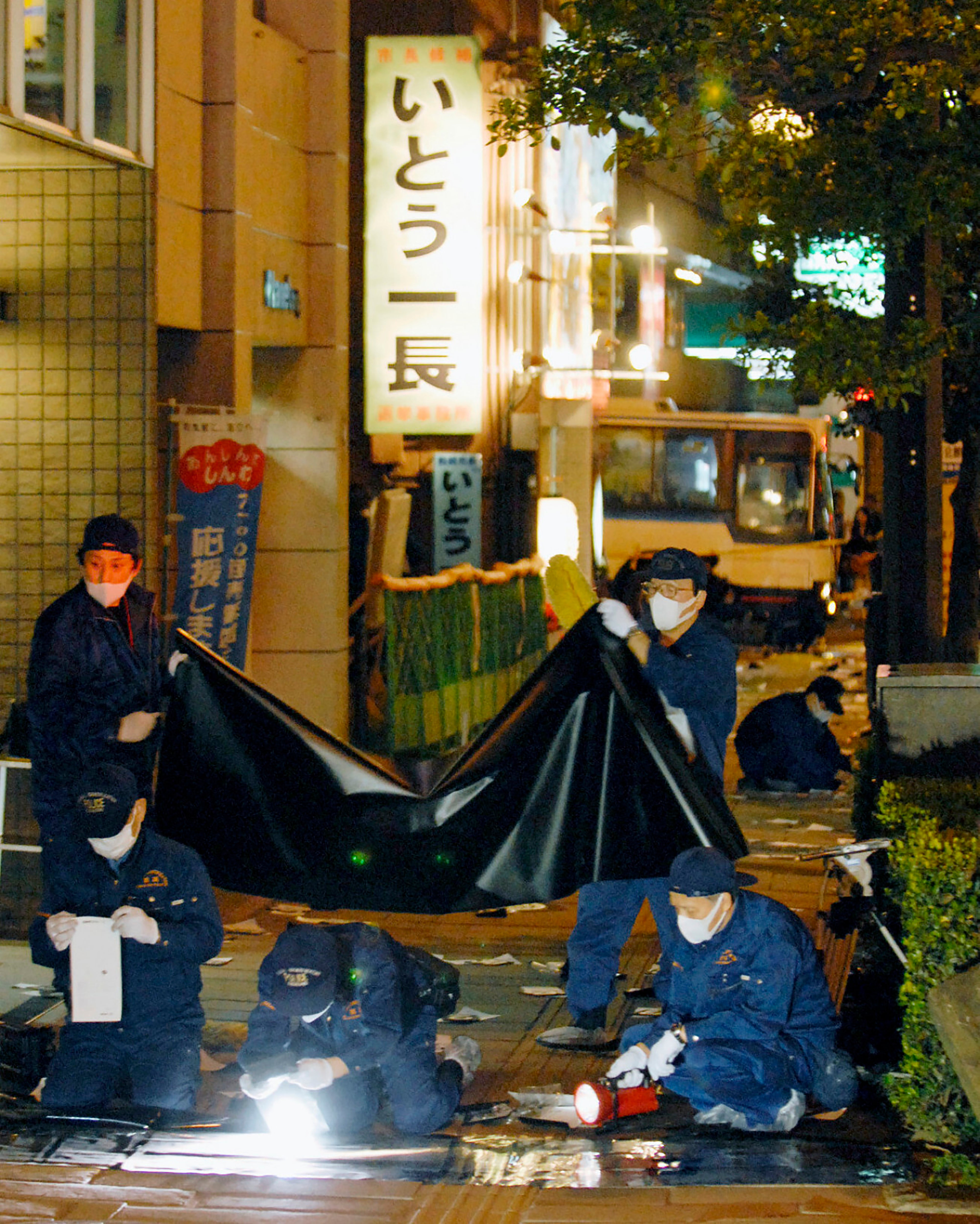 Police officers investigate at the site where Nagasaki Mayor Iccho Ito was assassinated by gunshot