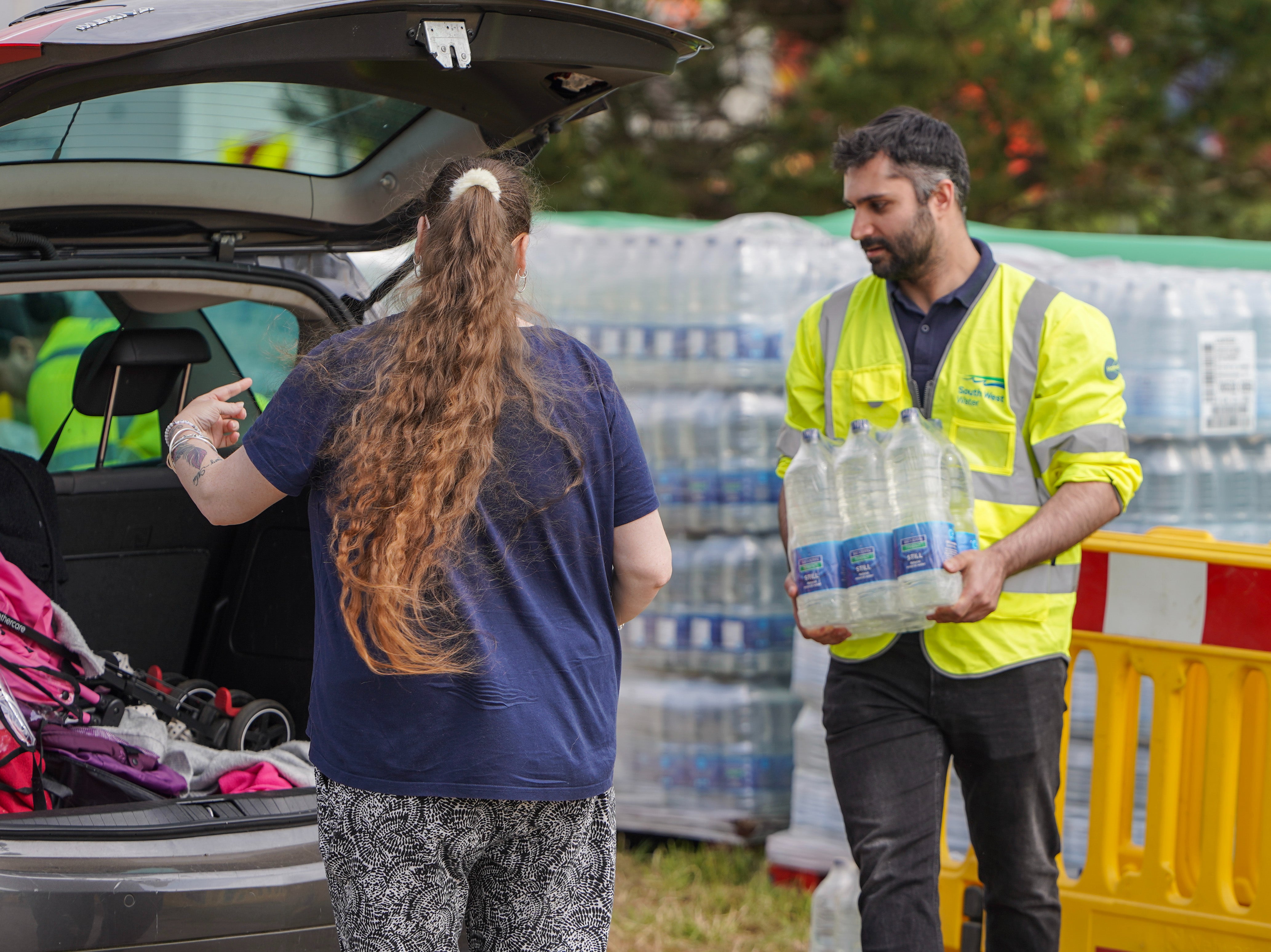 South West Water staff and volunteers distribute water to the public at a water collection point on May 18,