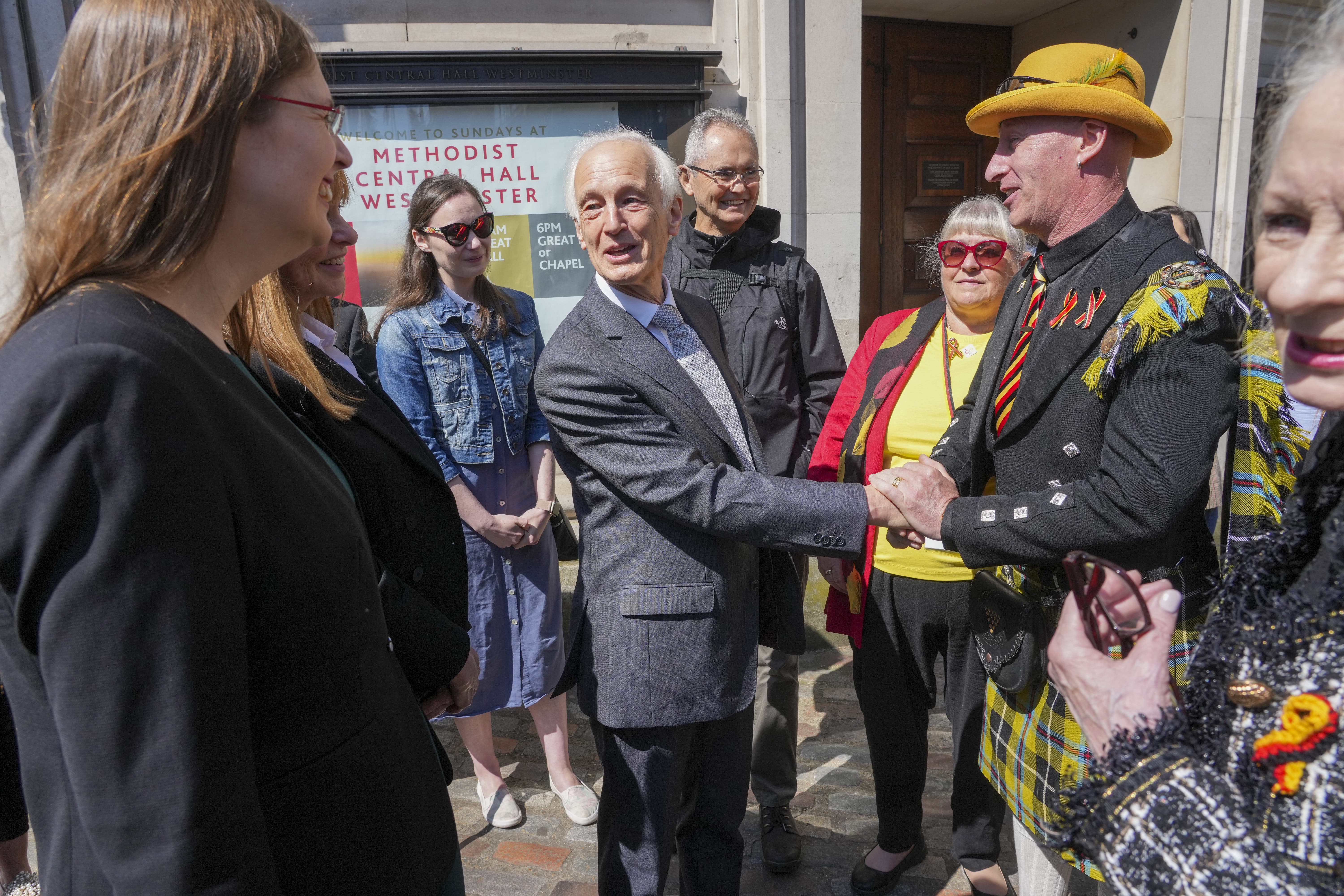 Chair of the Infected Blood Inquiry Brian Langstaff with victims and campaigners outside Central Hall in Westminster, London