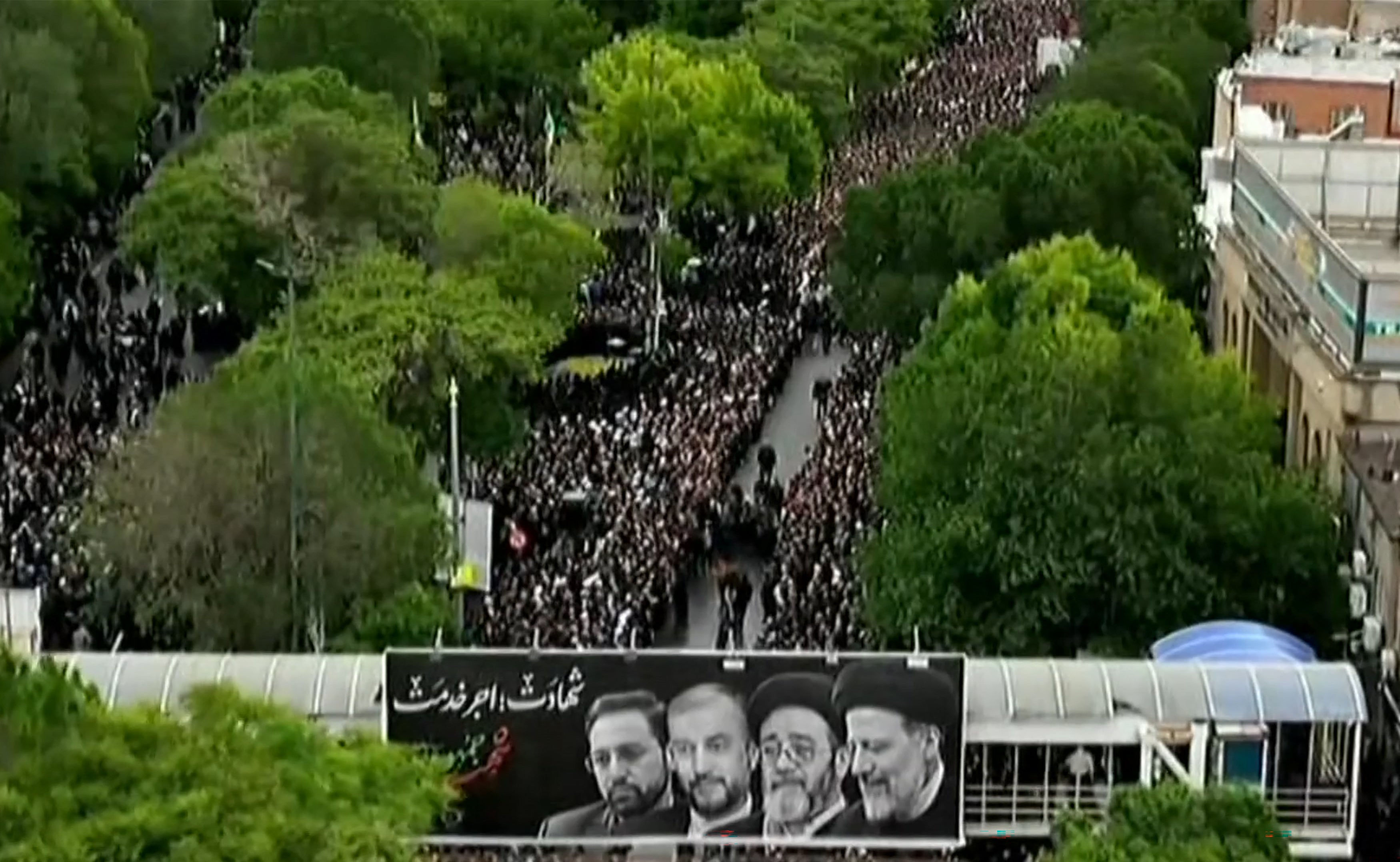 This grab taken from handout video footage released by Iran Press on May 21, 2024 shows people gathering to mourn the Iranian President and seven members of his entourage during a funerary procession