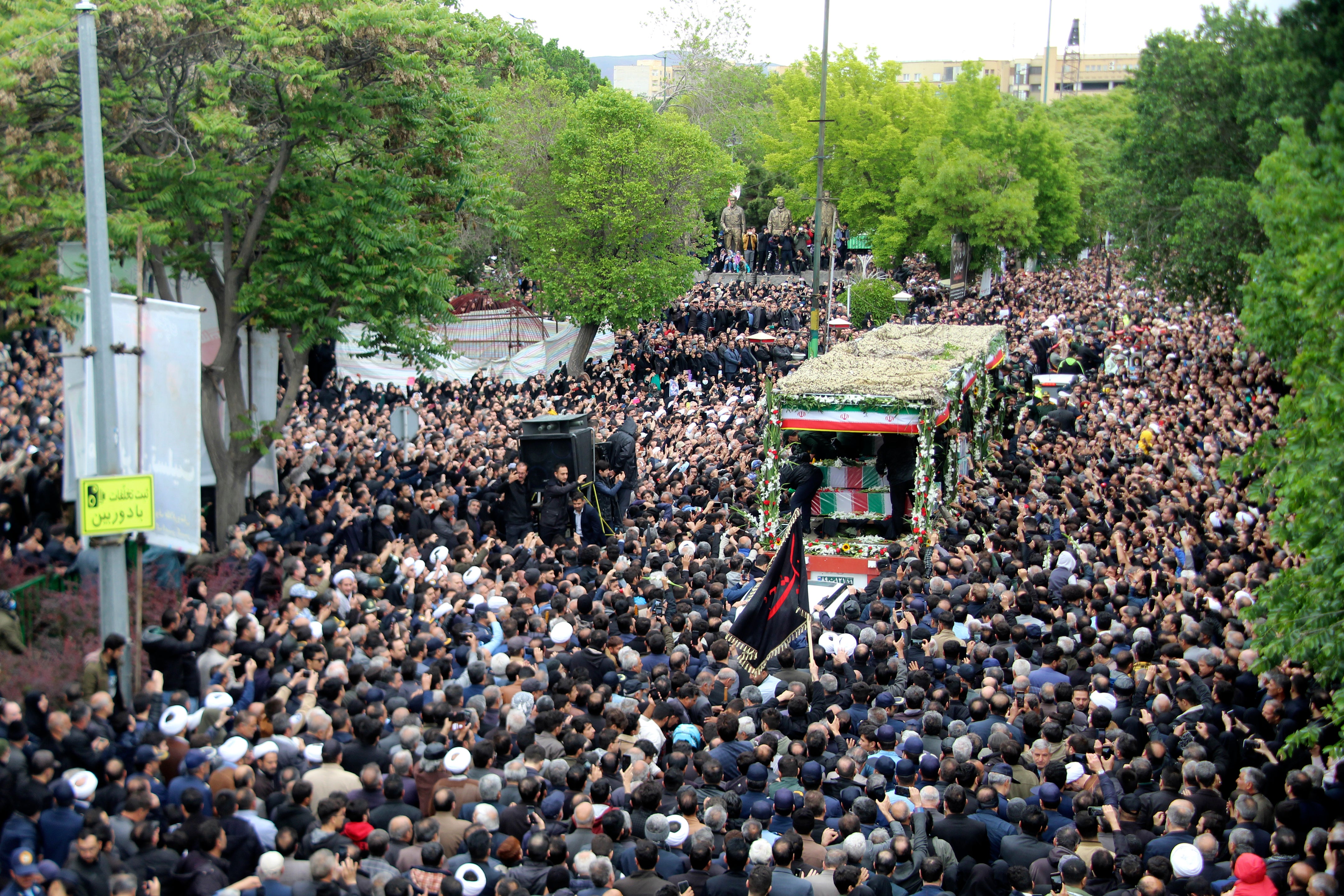 In this photo provided by Fars News Agency, mourners gather around a truck carrying coffins of Iranian President Ebrahim Raisi and his companions who were killed in a helicopter crash