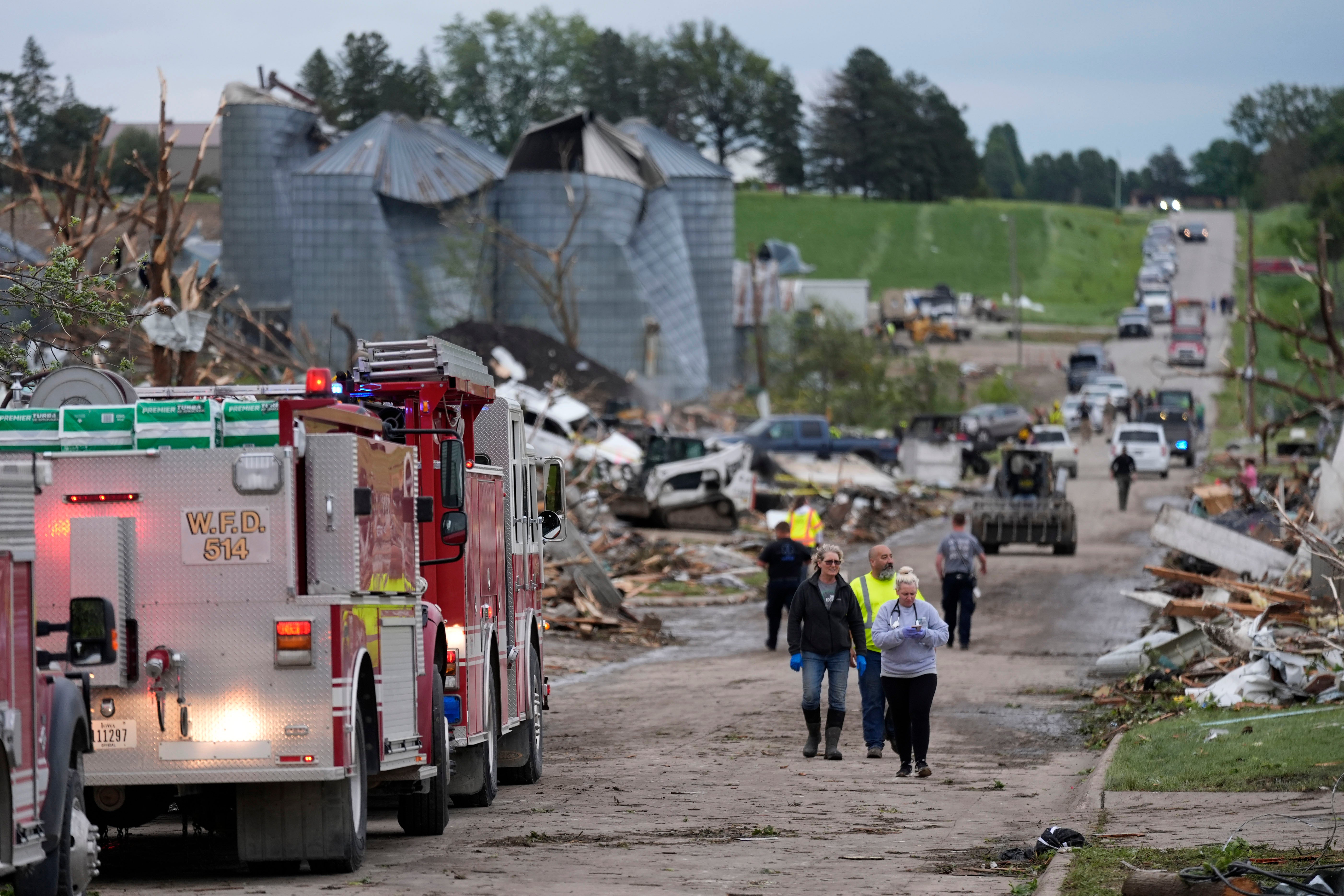 Rescue officials and residents walk down a street damaged by a tornado in Greenfield, Iowa, on Tuesday. The governor has committed to helping the town of just 2,000 rebuild