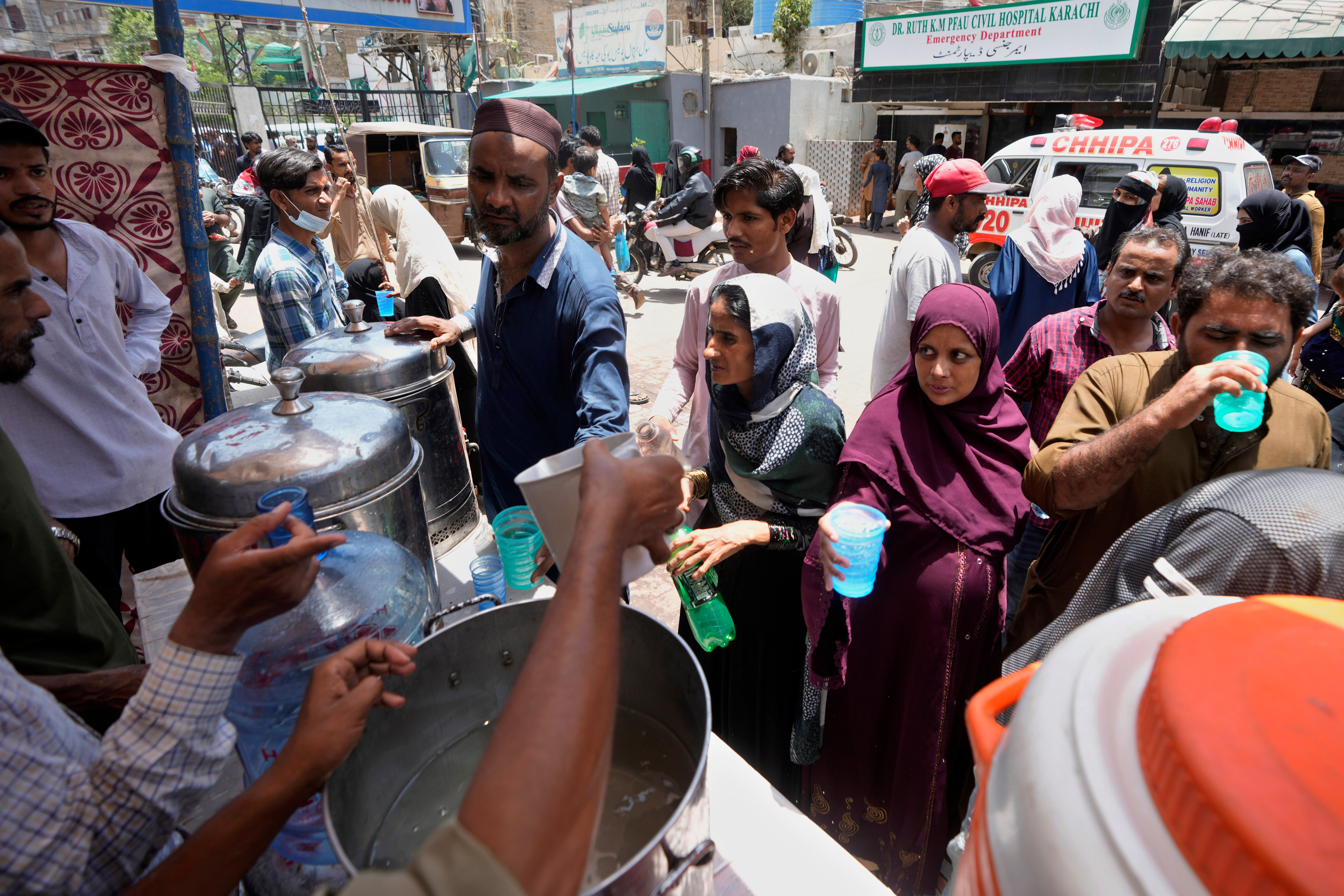 Volunteers provide lime sugar water to people at a camp set up to prevent heat stroke on a hot summer day, in Karachi, Pakistan