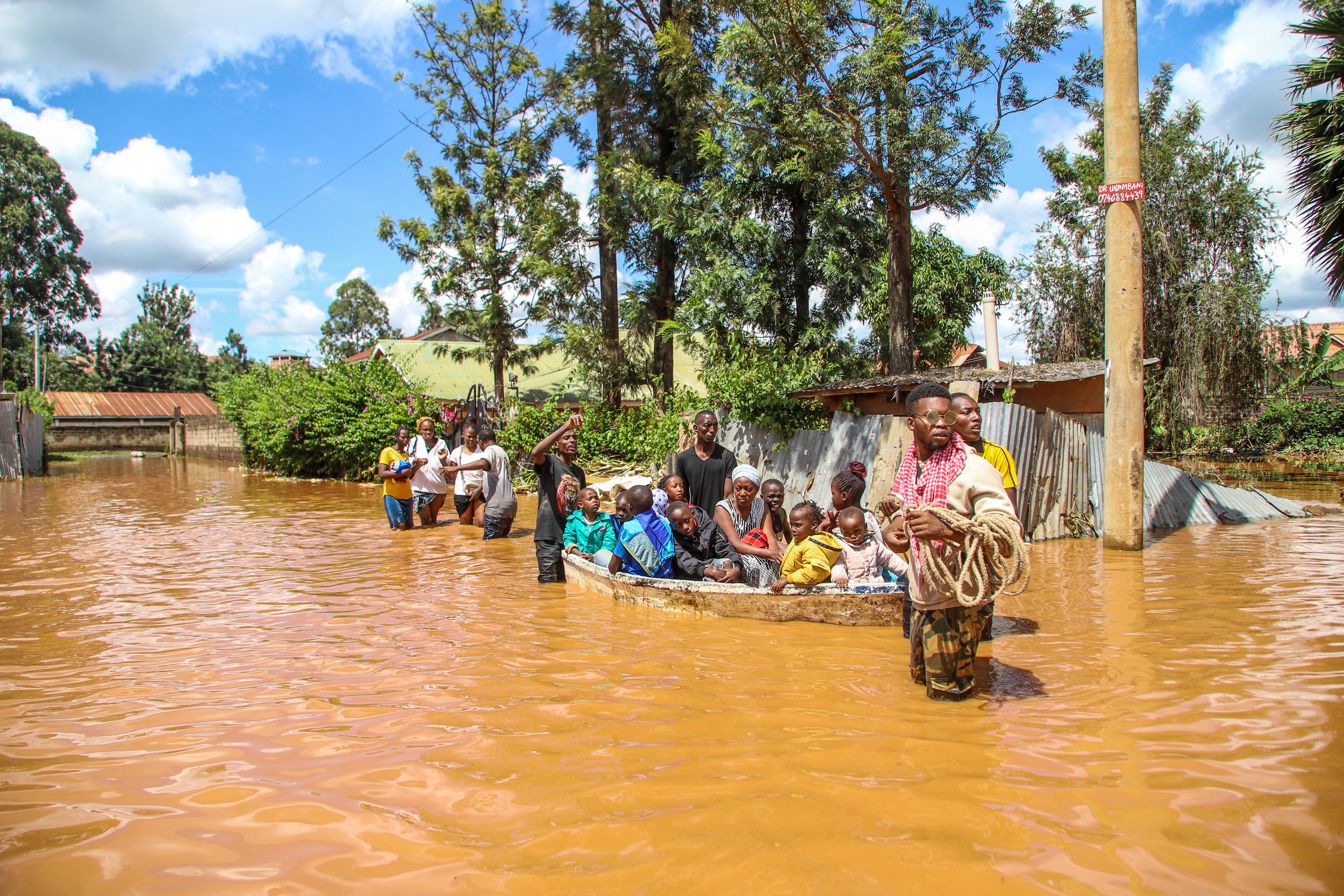A family uses a boat to navigate floodwaters in Githurai, Kenya