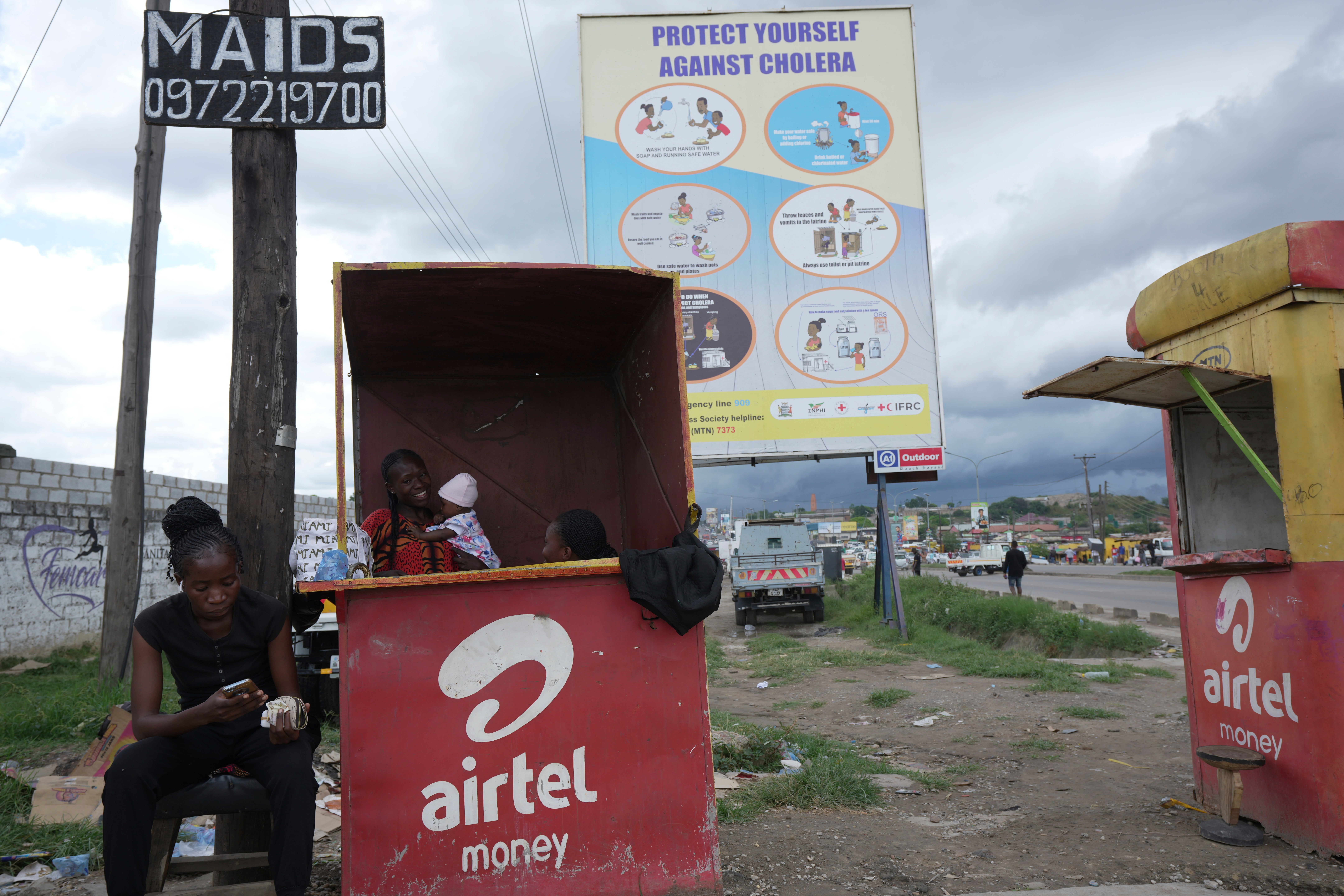 Street vendors in Lusaka, Zambia sell phone cards underneath a billboard urging people to protect themselves from cholera