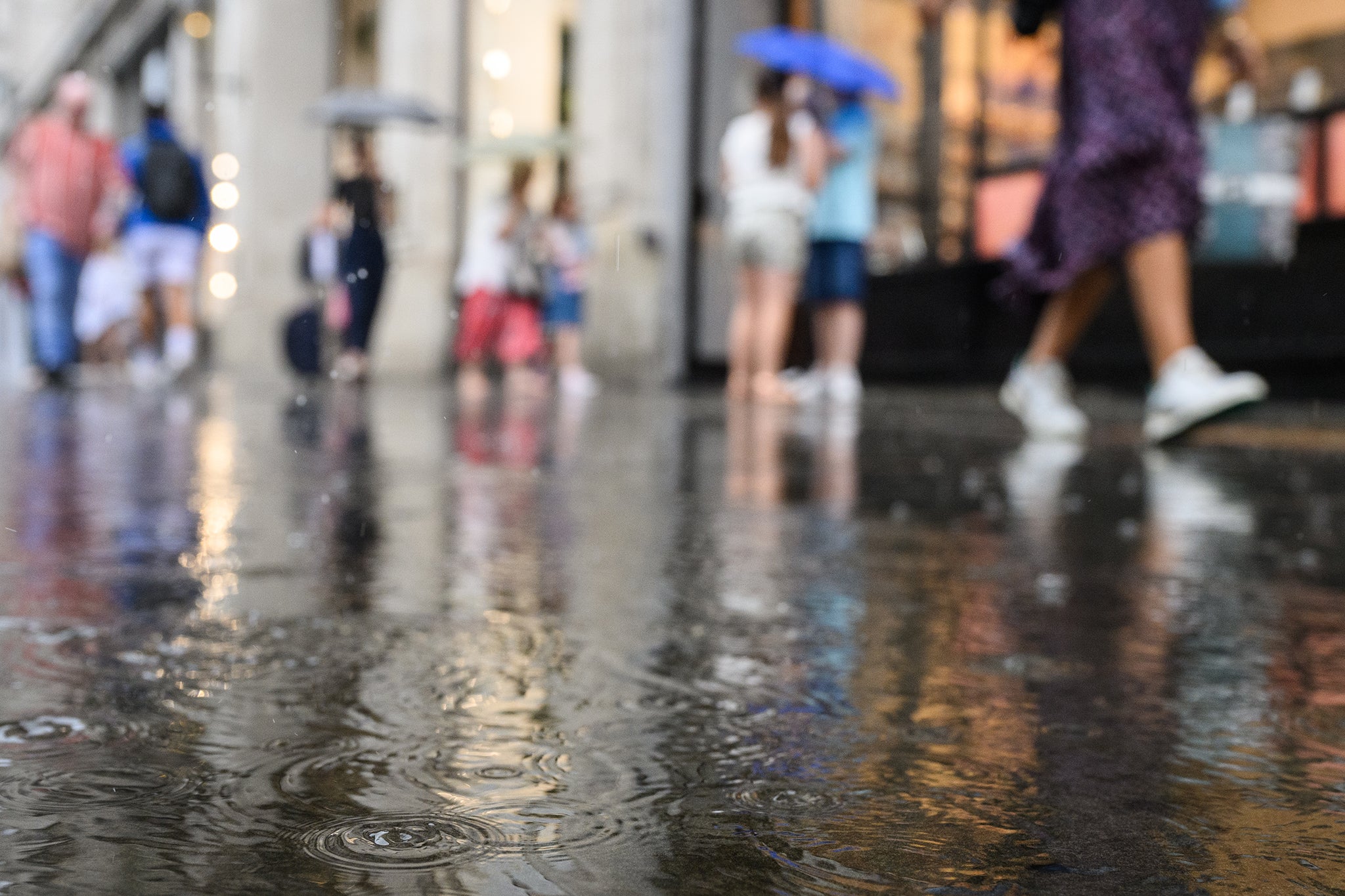 Raindrops land in a puddle as shoppers rush through a heavy downpour on August 16, 2022 in London, England