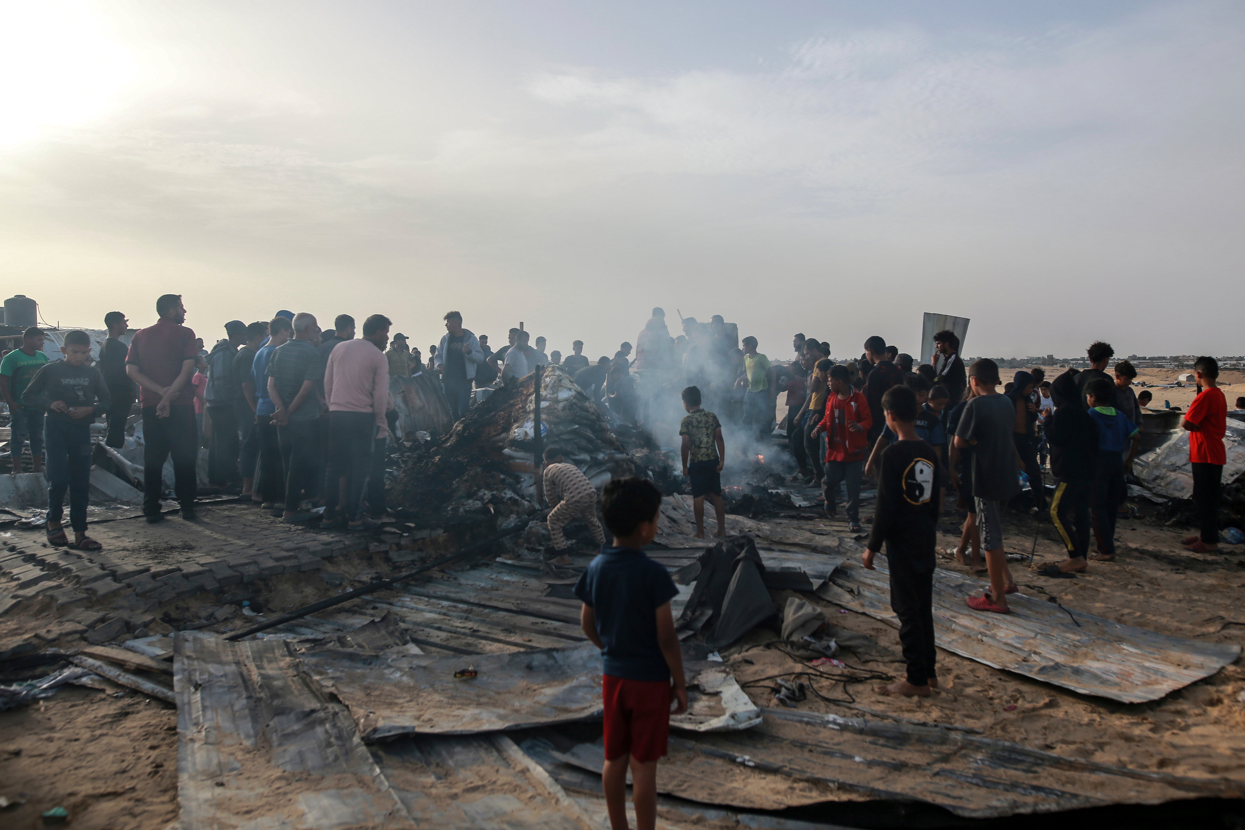 Palestinians look at the destruction after an Israeli strike where displaced people were staying in Rafah