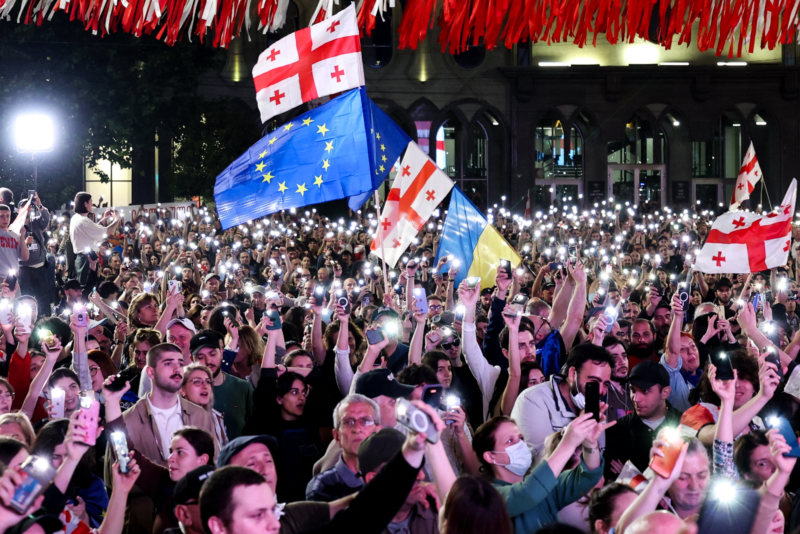 People hold smartphones with flashlights as they protest the ‘foreign influence’ law outside the parliament building in Tbilisi