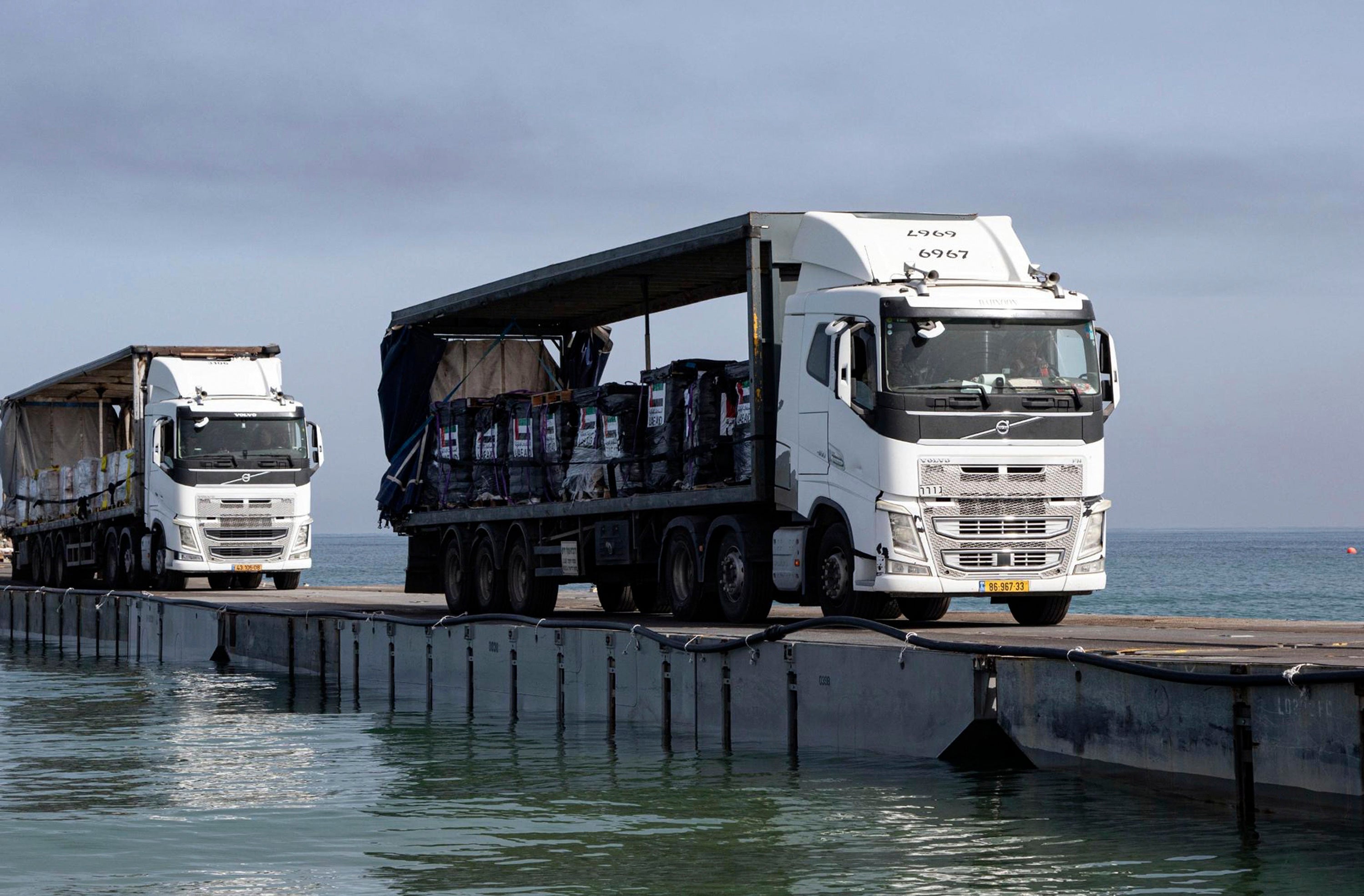 This image provided by the U.S. Army shows trucks loaded with humanitarian aid from the United Arab Emirates and the United States Agency for International Development cross the Trident Pier before arriving on the beach on the Gaza Strip, May 17, 2024