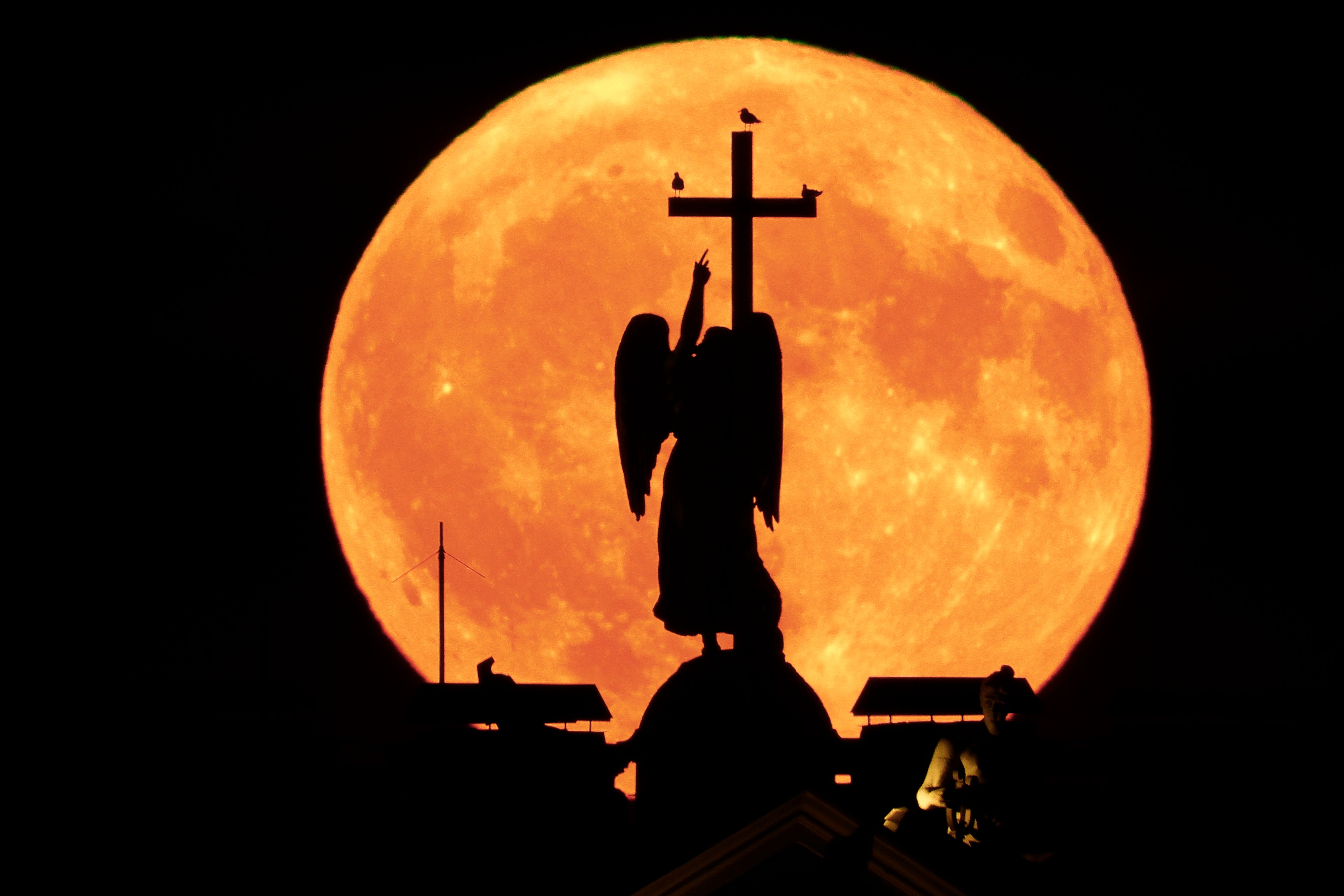 The full Moon rises over the Alexander Column at the Palace Square in St Petersburg, Russia, late Thursday, 23 May, 2024
