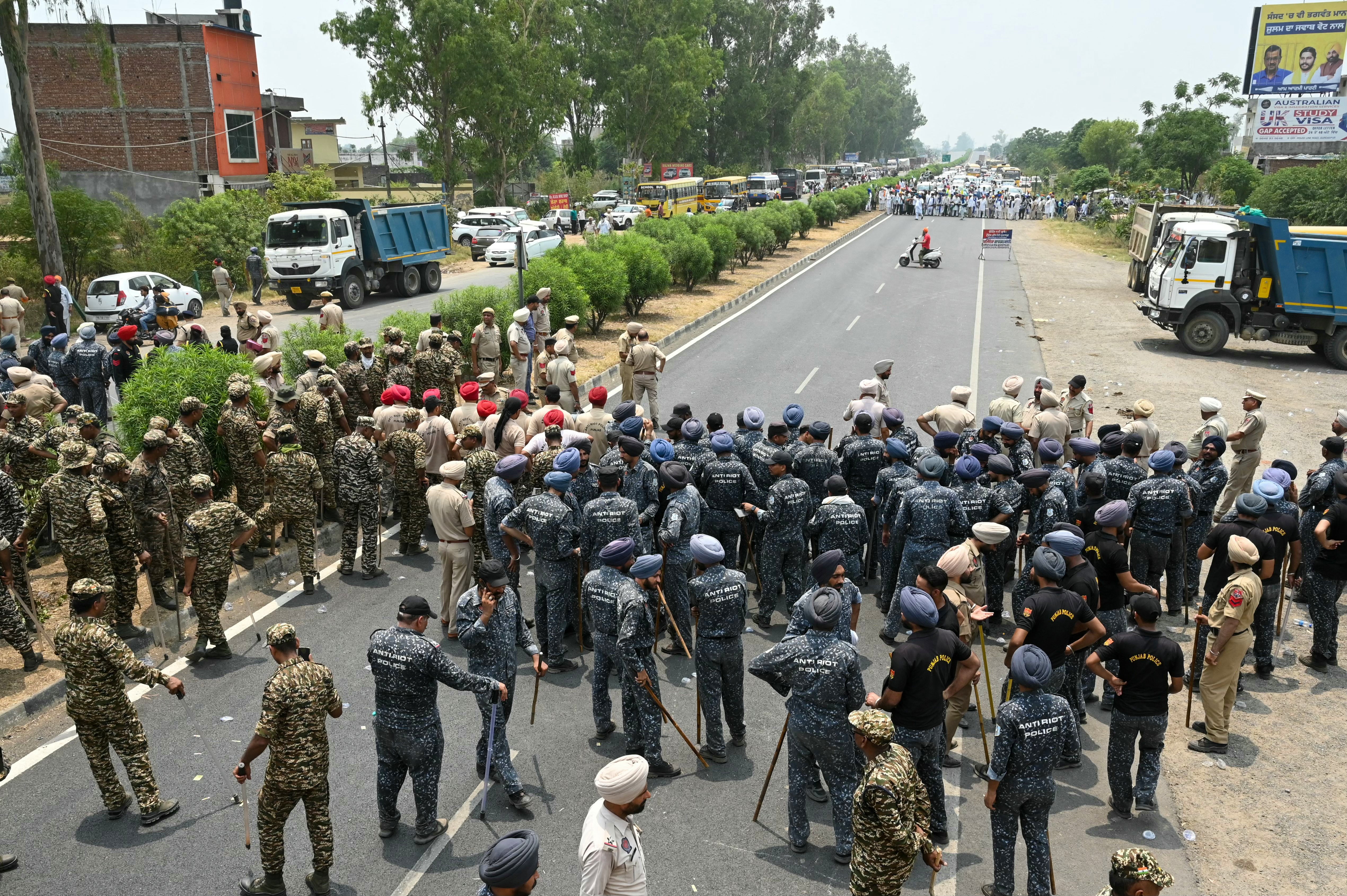 Anti riot police stand guard as farmers march to protest against India’s Prime Minister and leader of the ruling Bharatiya Janata Party (BJP) Narendra Modi, to demand minimum crop prices on the outskirts of Gurdaspur