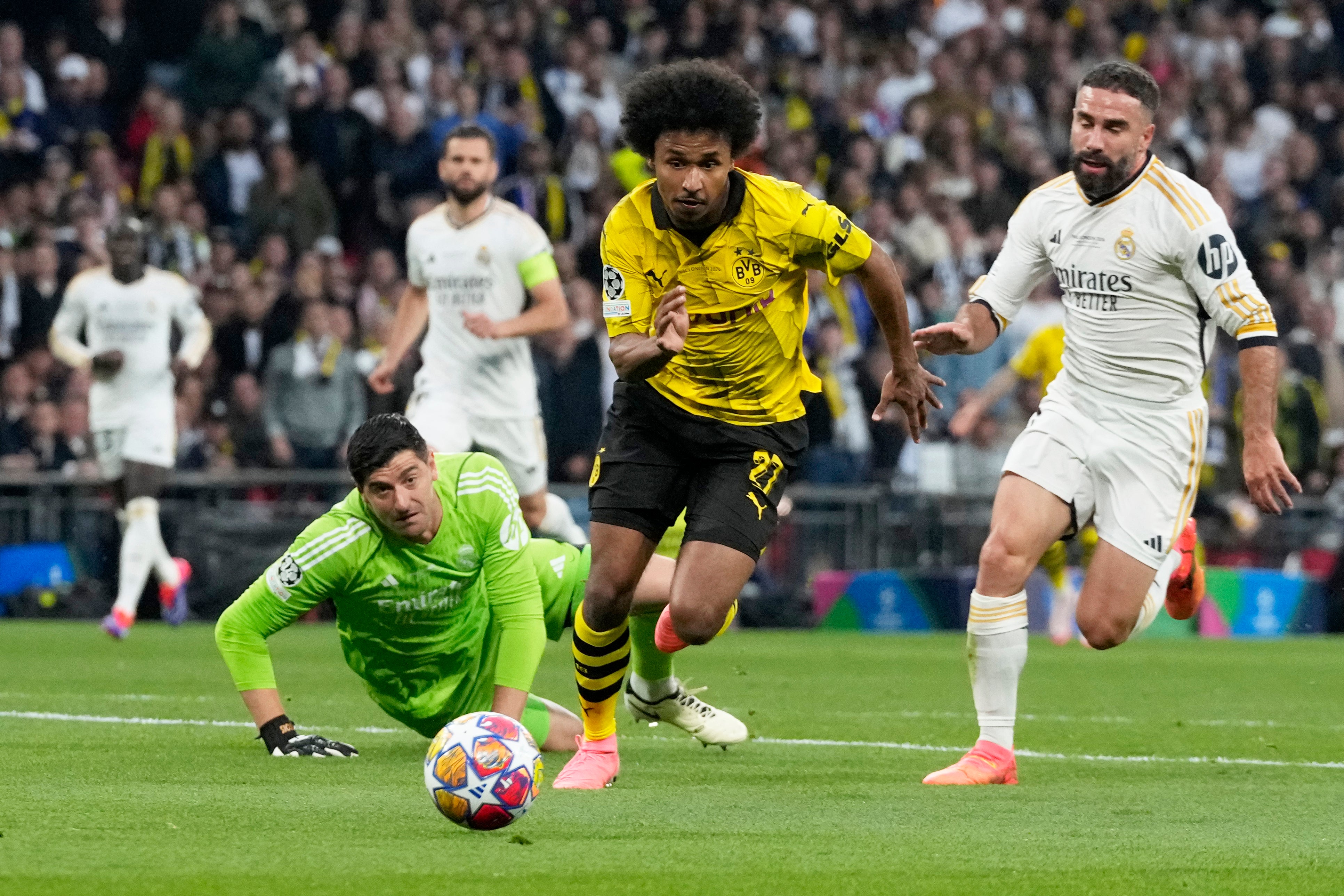 Dortmund's Karim Adeyemi, centre, gets past Real Madrid's goalkeeper Thibaut Courtois