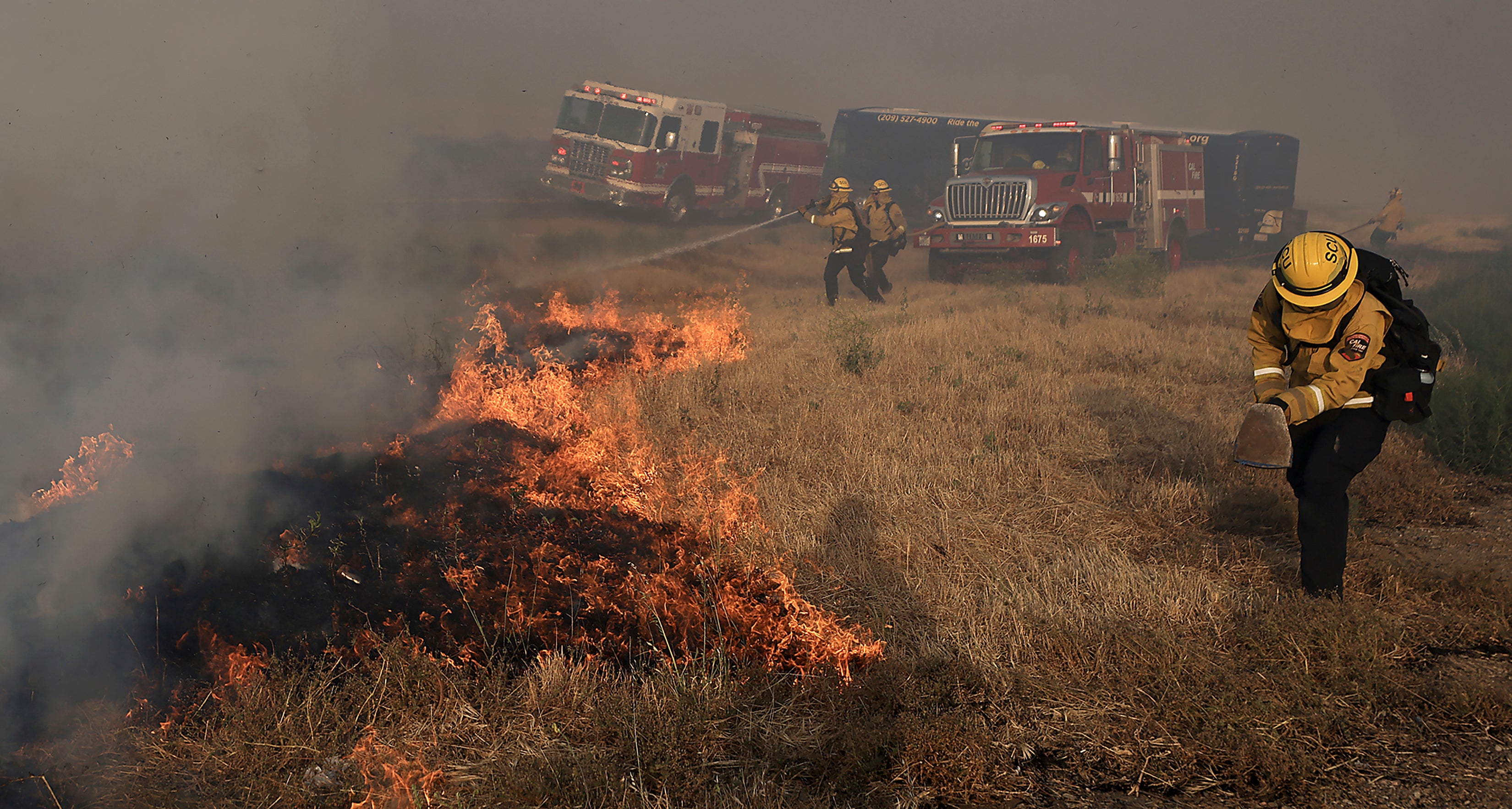 A Santa Clara Cal Fire crew scrambles to extinguish a spot fire in the median of Interstate 580, during the Corral Fire west of Tracy, Calif., Saturday, June 1, 2024