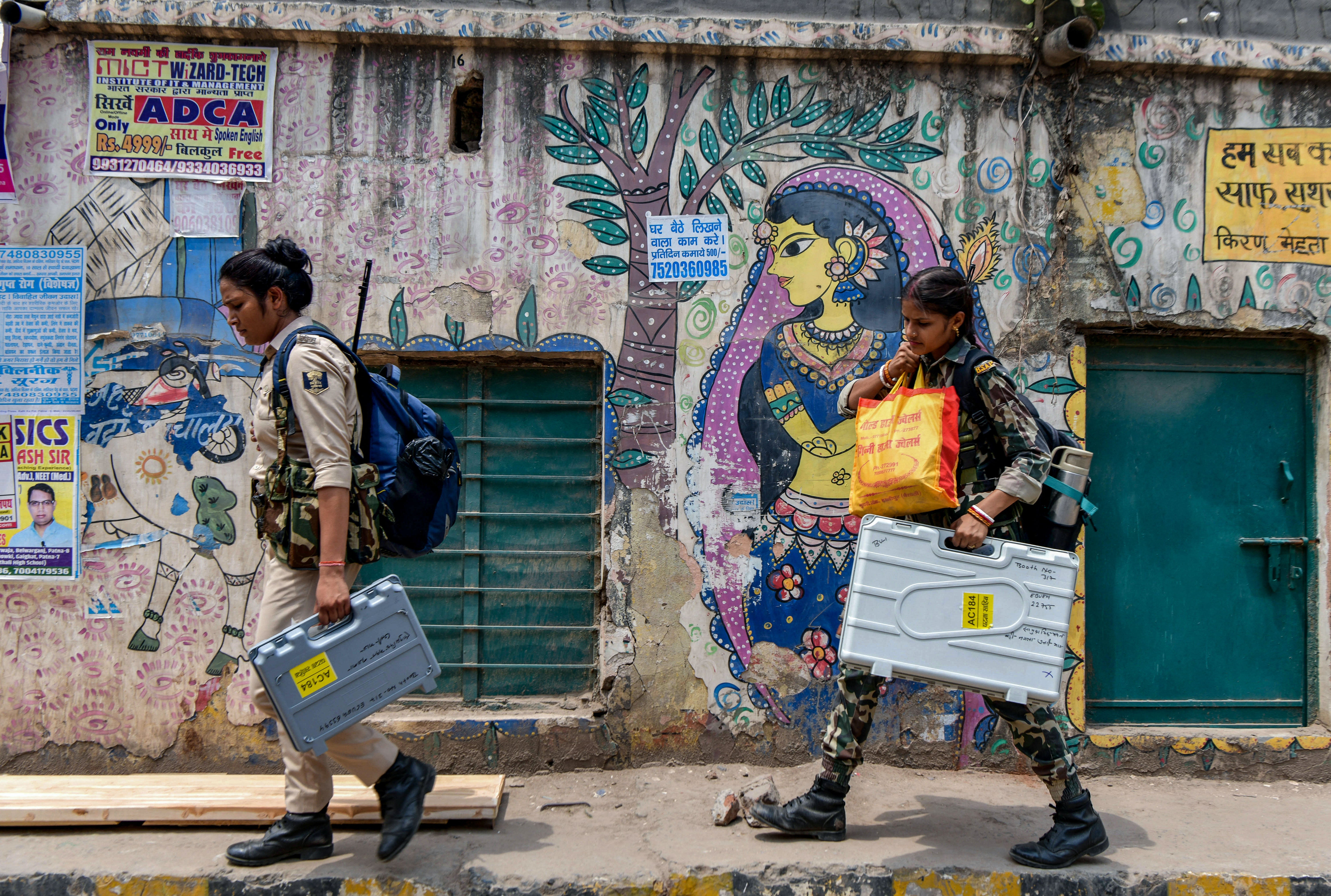 Security workers carry electronic voting machines and other voting materials in Patna on Friday