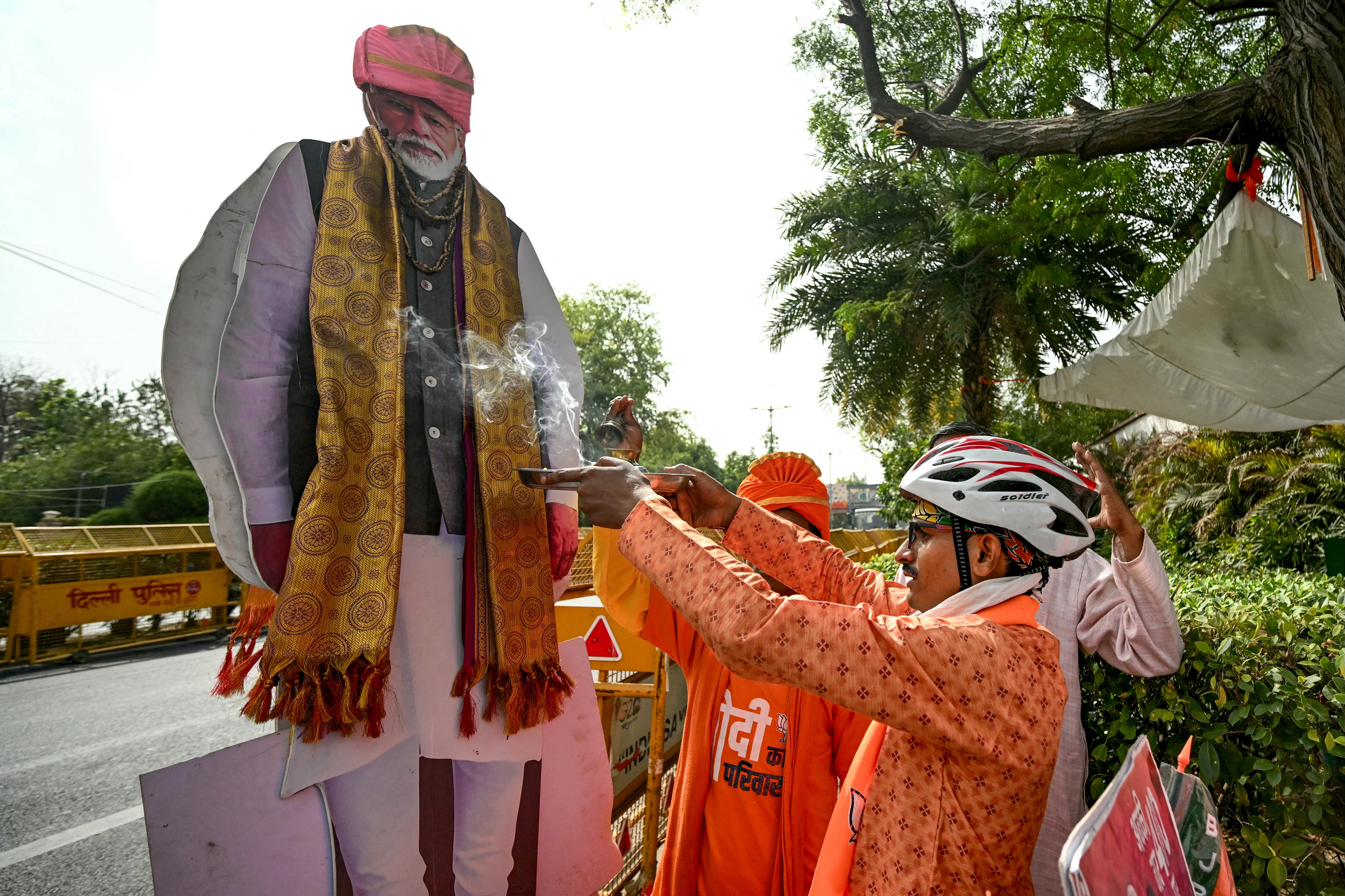 A supporter of Narendra Modi performs rituals with the prime minister’s cutout outside the BJP headquarters in New Delhi