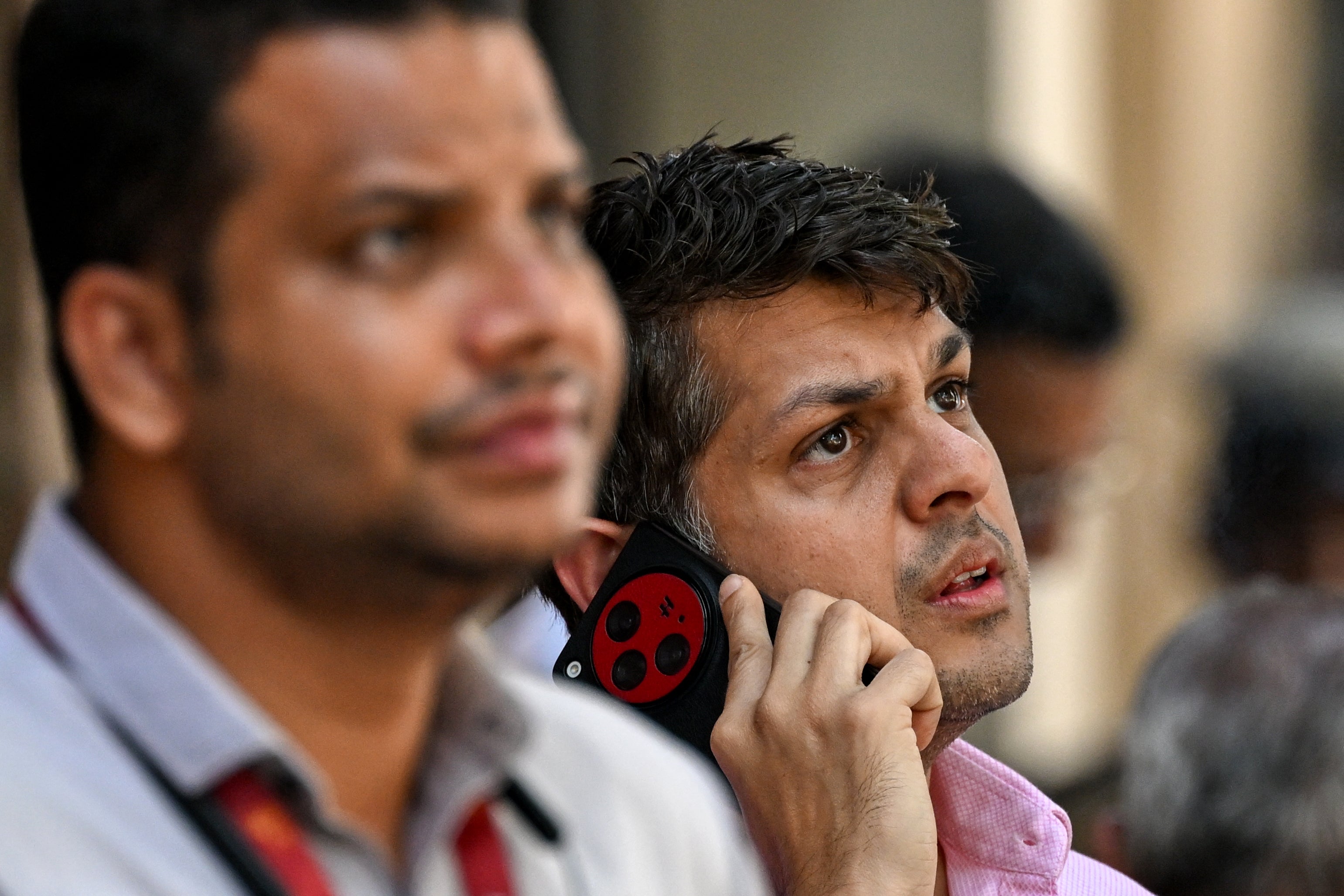 Pedestrians watch share prices on a digital broadcast outside the Bombay Stock Exchange