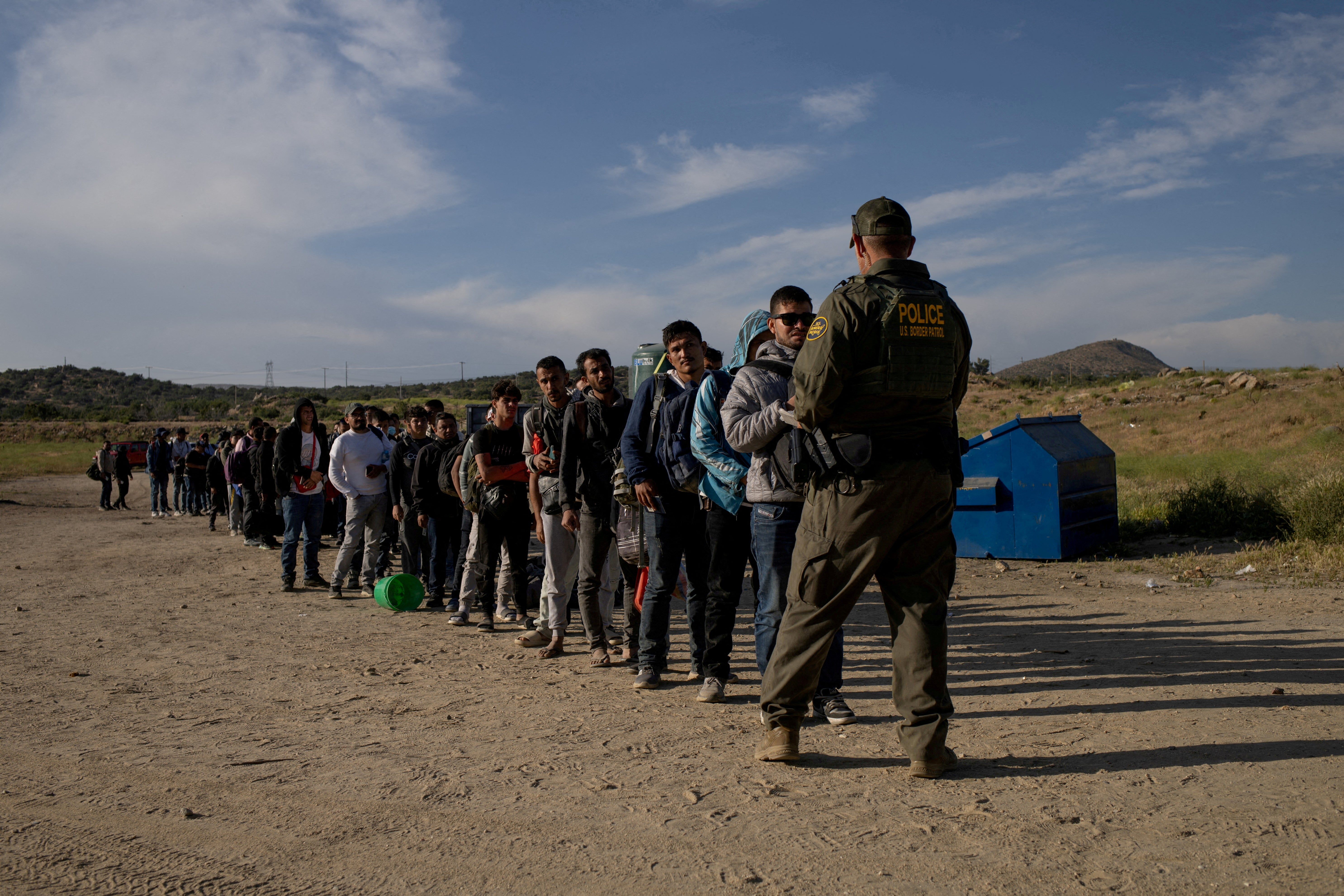 Immigrants surrender to a border agent at the US-Mexico border in California on May 15.