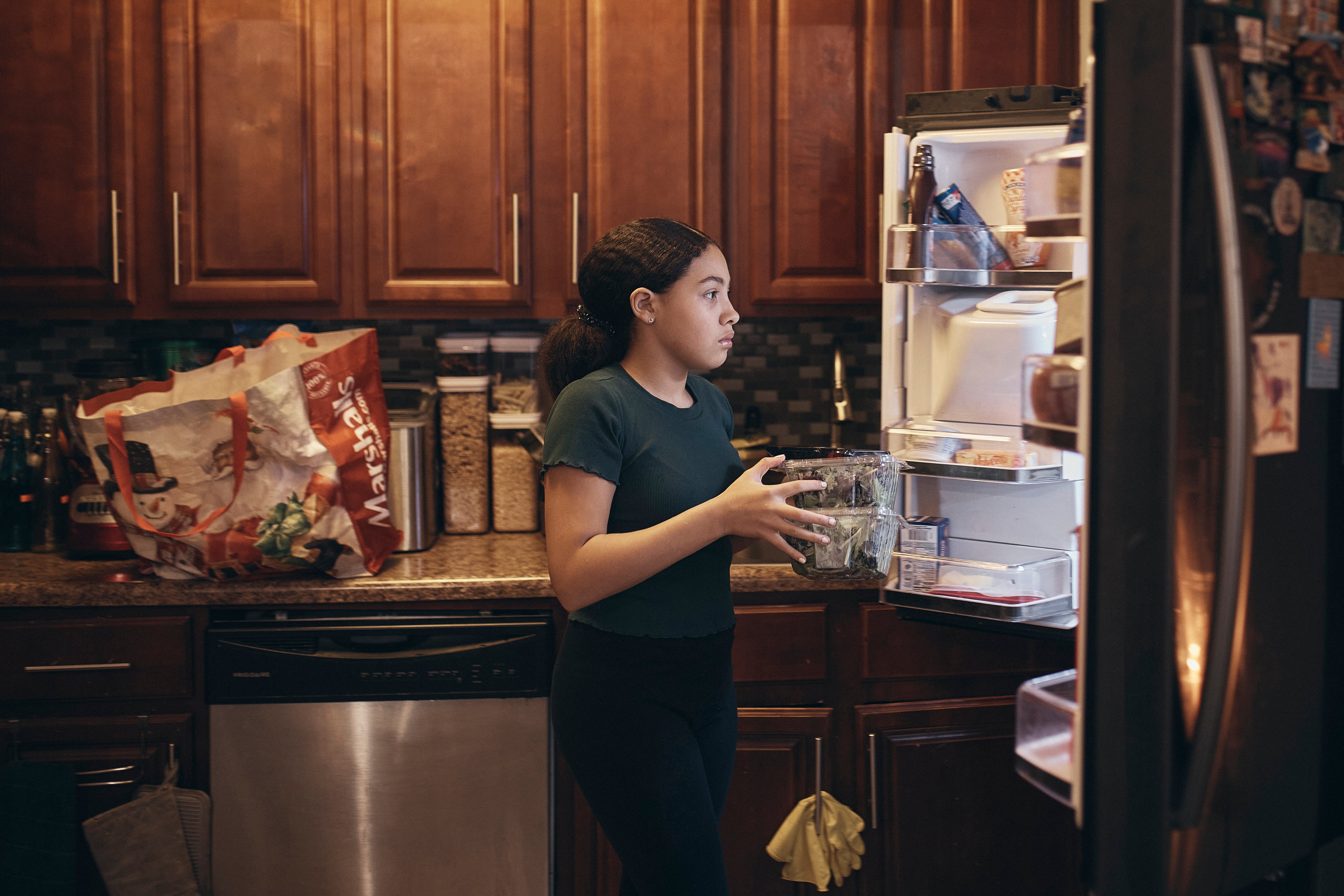 Grace Durham, 11, helps her mother, Elena Romero, not pictured, to put groceries in the refrigerator