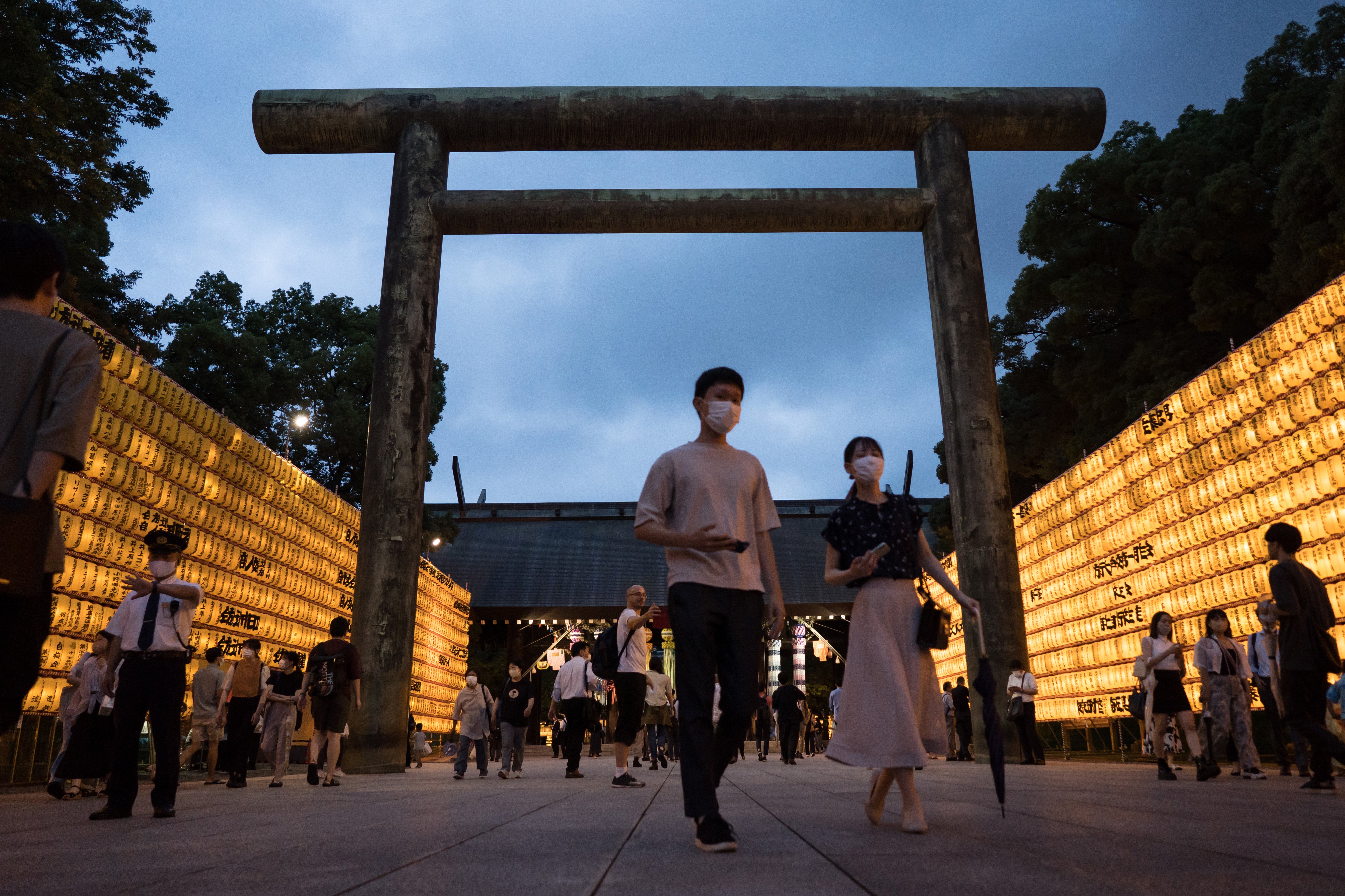 File: People walk past lit paper lanterns during the Mitama Matsuri summer festival at the Yasukuni Shrine