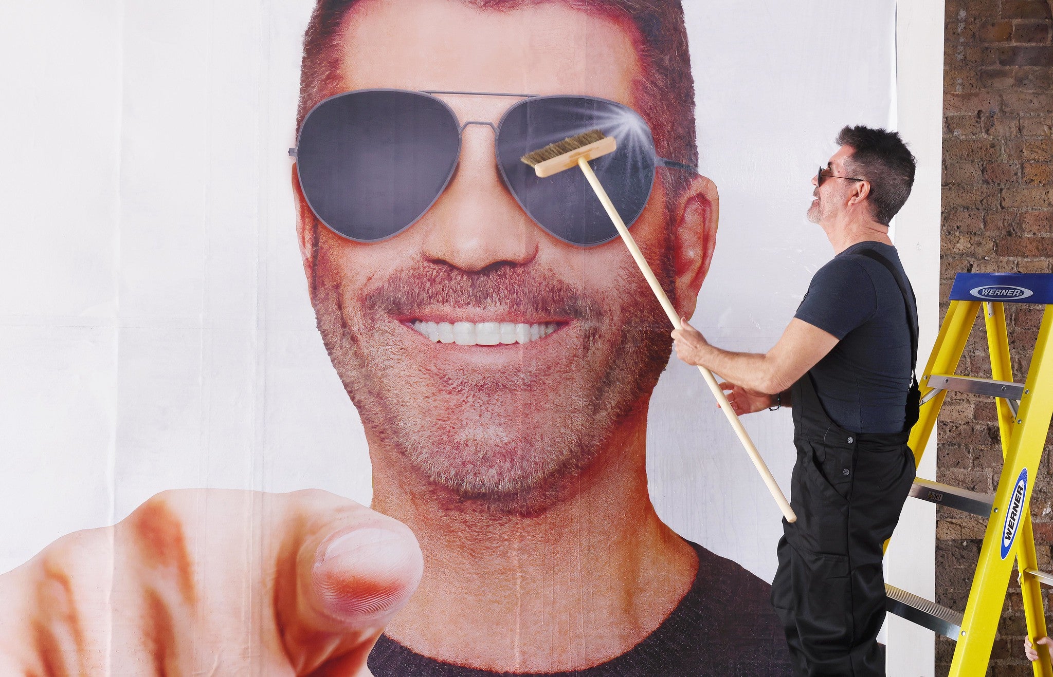 Simon Cowell puts up a billboard as part of his search for the UK’s next boyband