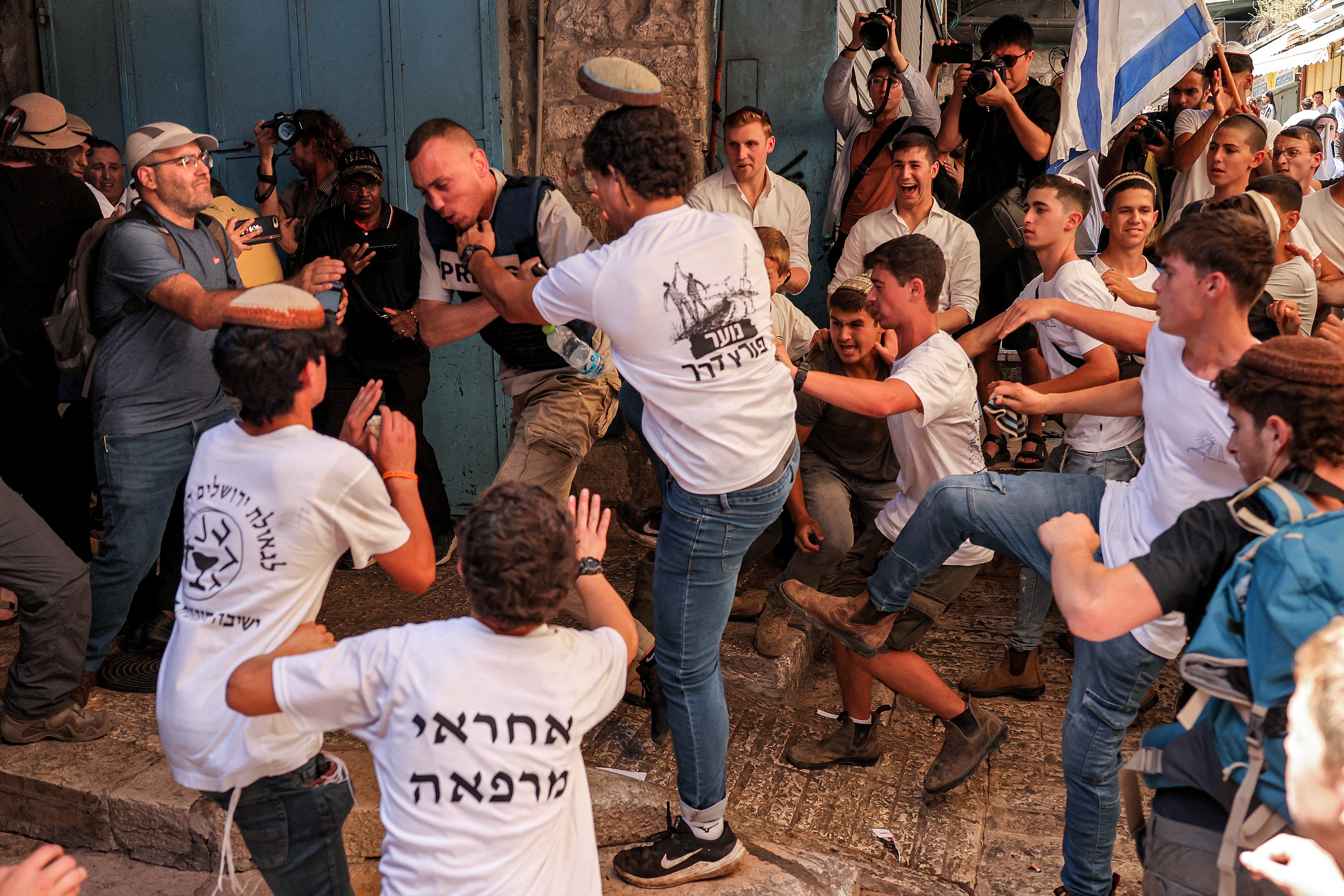 Young men on the march grab a journalist during a march commemorating Jerusalem Day