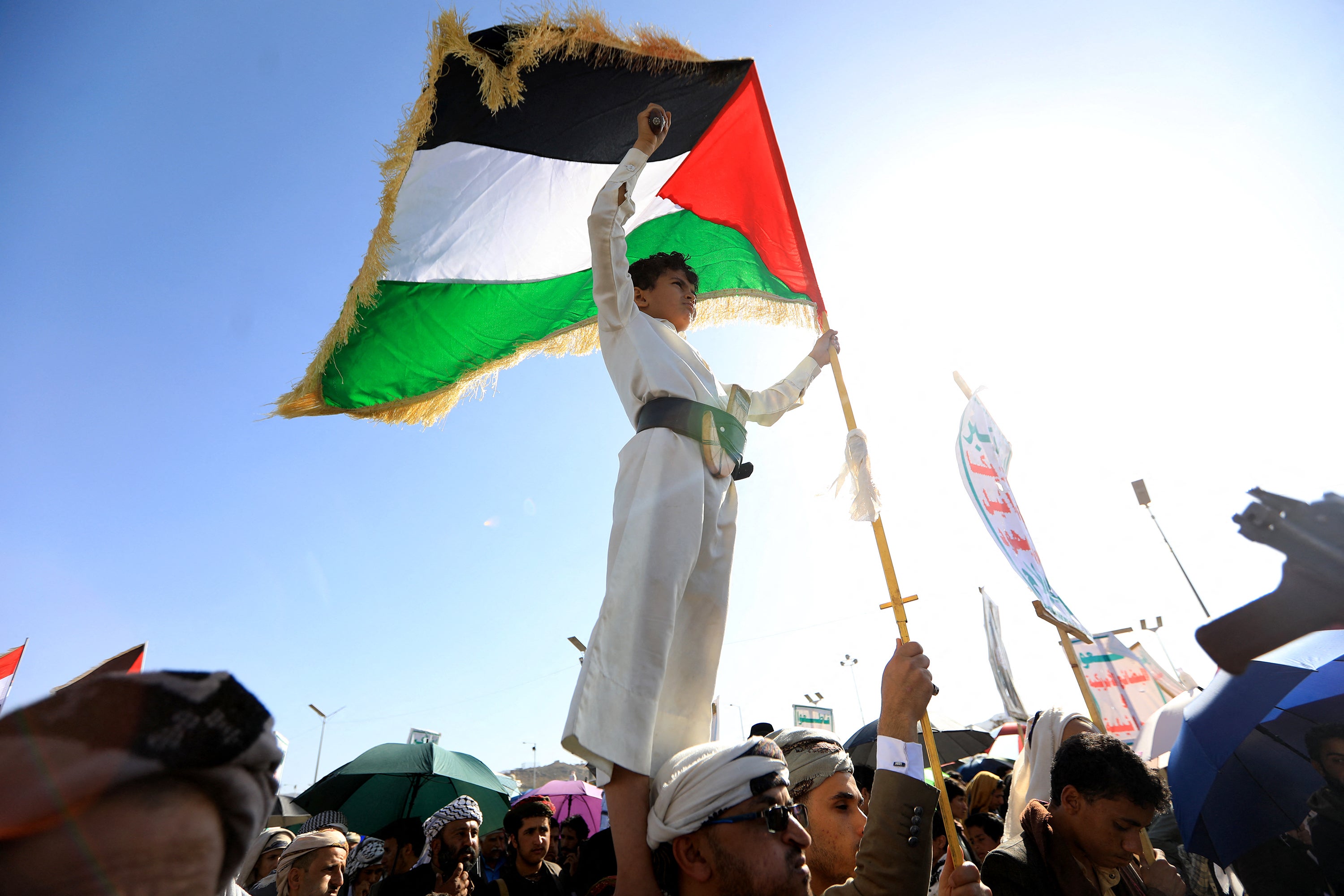 A Yemeni child stands on the shoulders of a man as he holds onto a Palestinian flag during a solidarity march with the Palestinian people of the Gaza Strip, in the Huthi-run capital Sanaa on 7 June