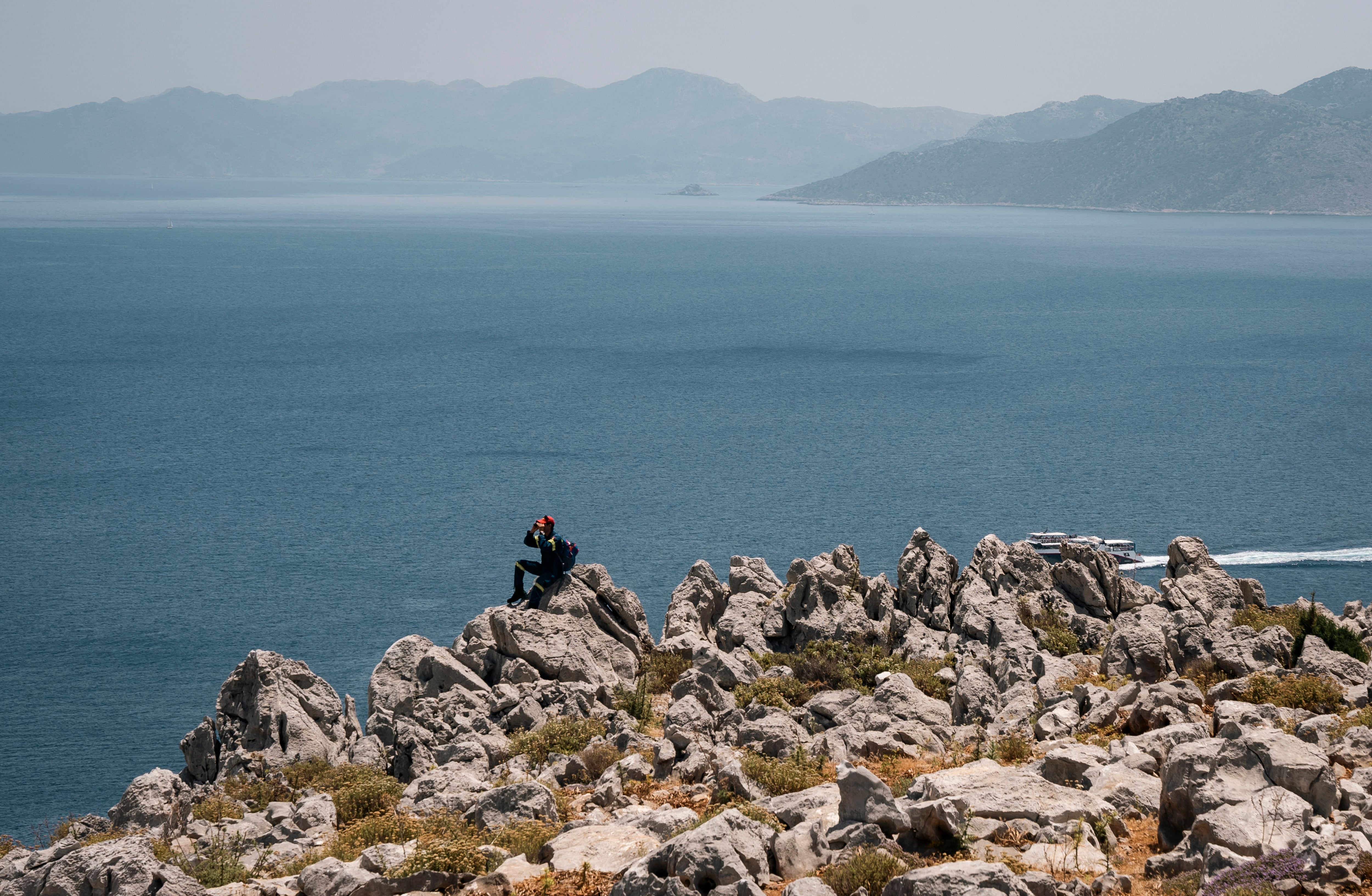 A firefighter sits on a rock during a search and rescue operation for Michael Mosley who was last seen on Wednesday