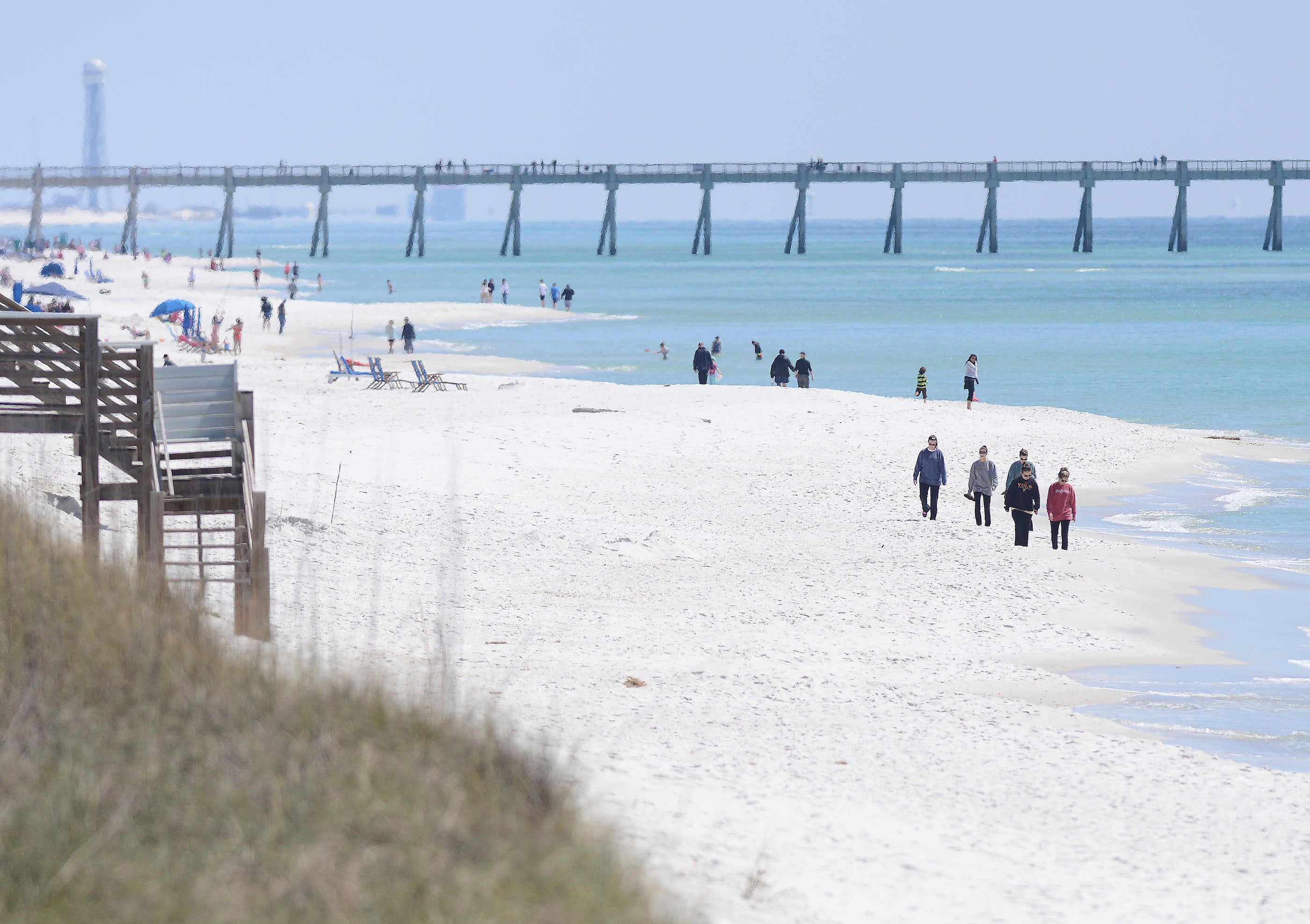 People walk along the shoreline in Navarre Beach