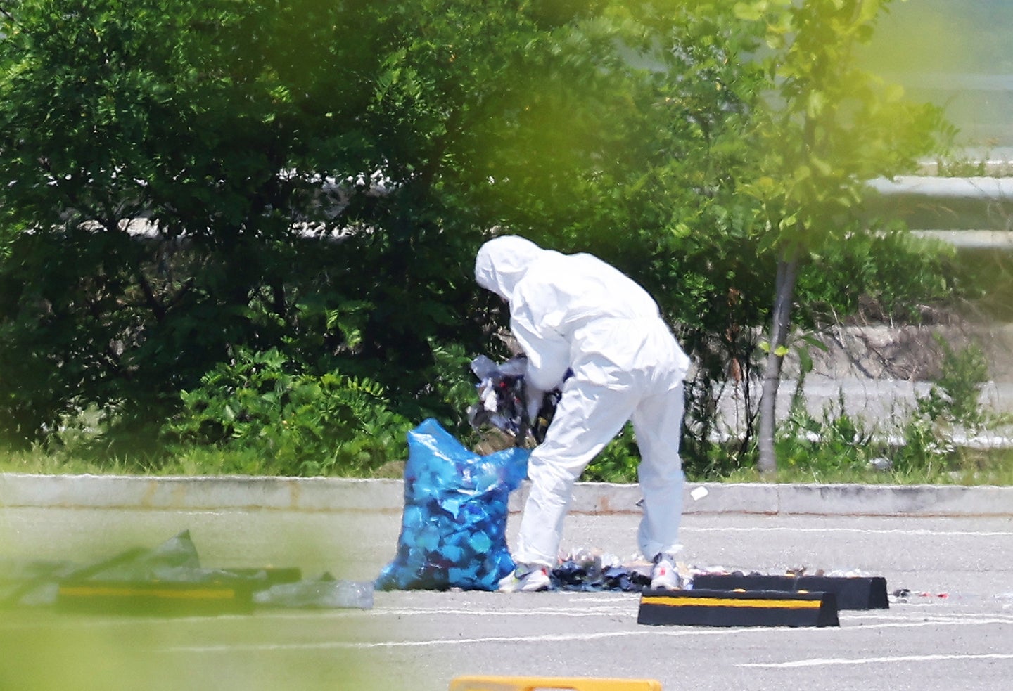 An officer wearing protective gear collects the trash from a balloon presumably sent by North Korea