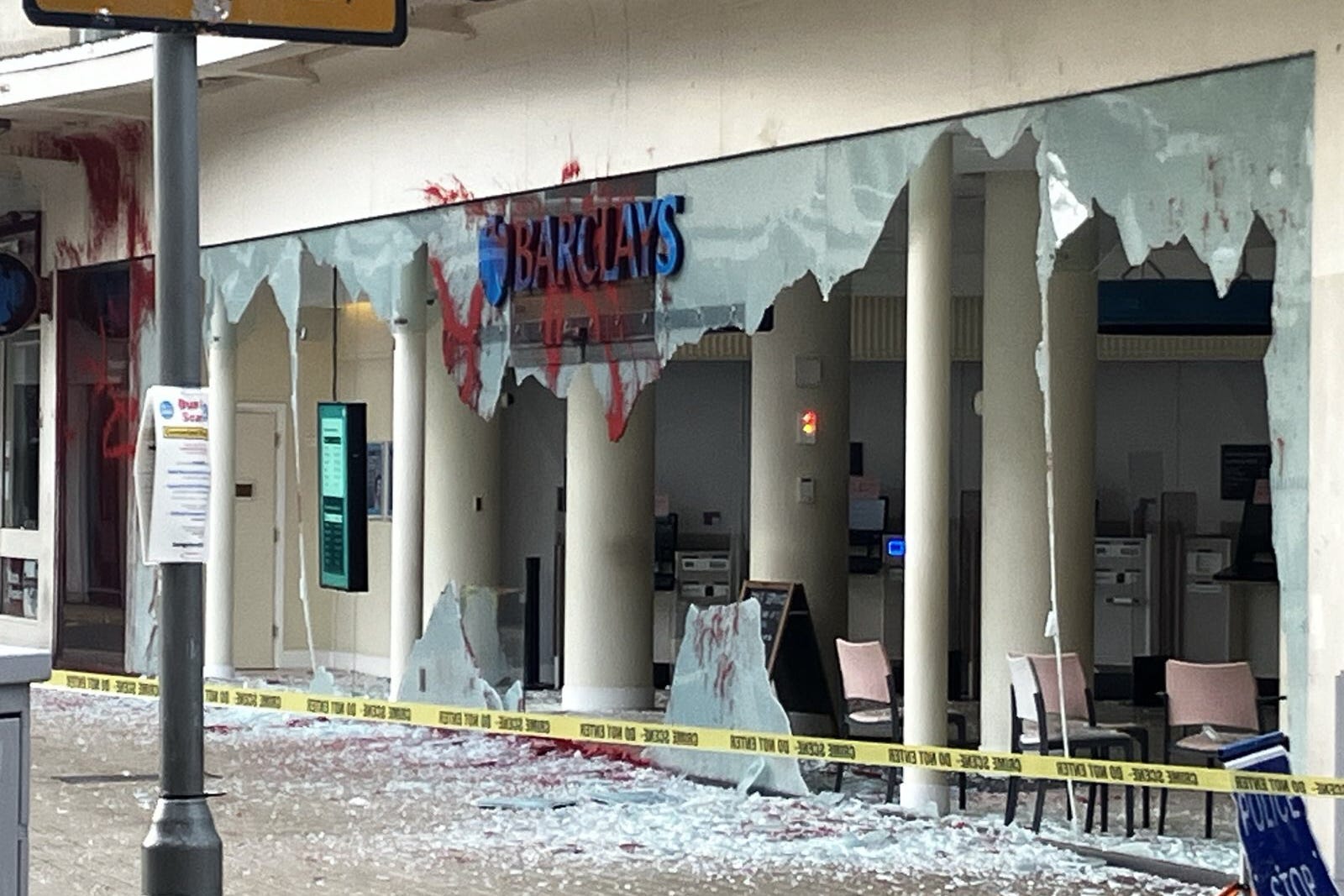 The windows of a branch of Barclays in Bristol are completely smashed, with red paint visible on the bank sign