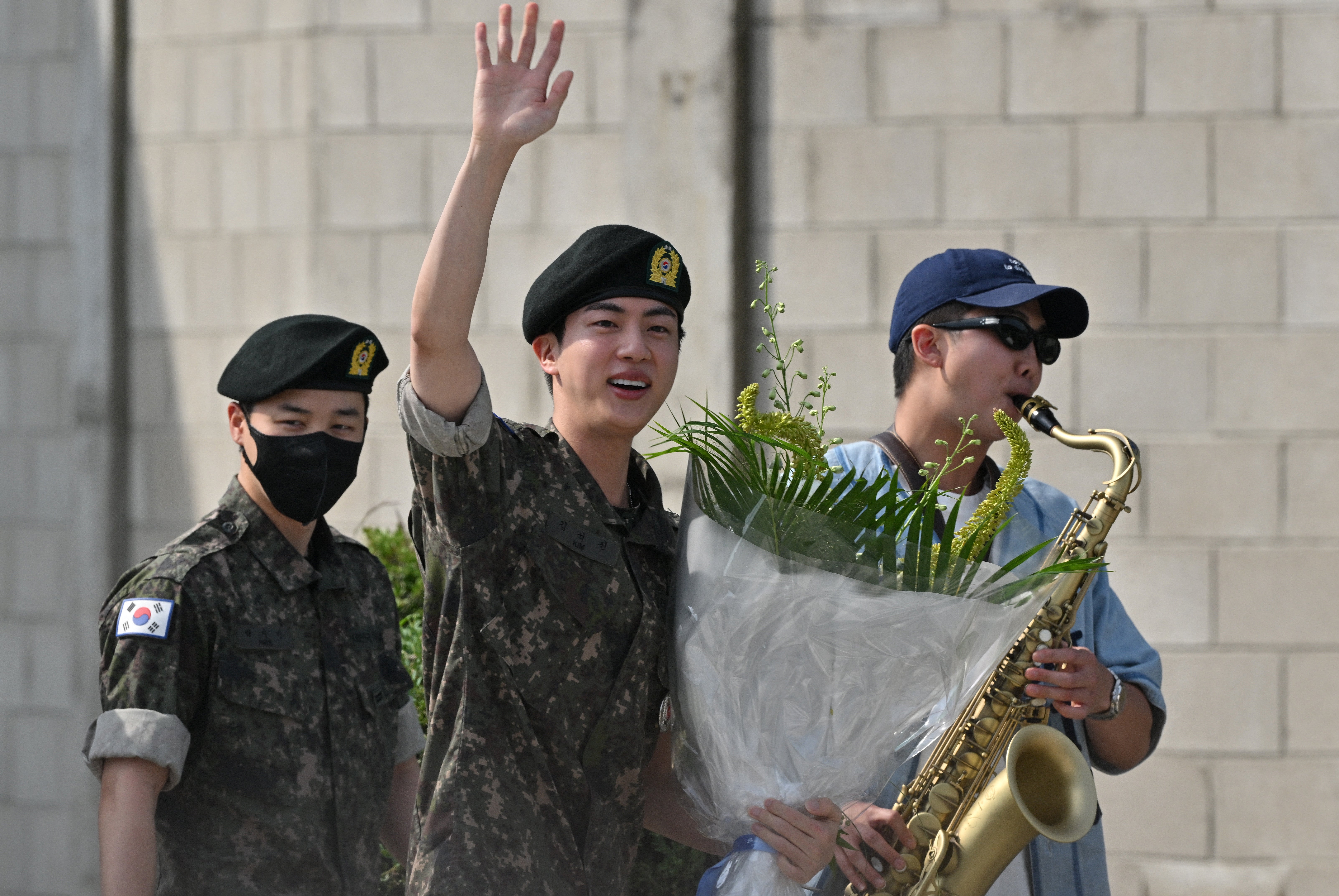 K-pop boy band BTS member Jin (C) waves after being discharged from his mandatory military service next to fellow BTS members RM (R) and Jimin (L) outside a military base in Yeoncheon on 12 June, 2024