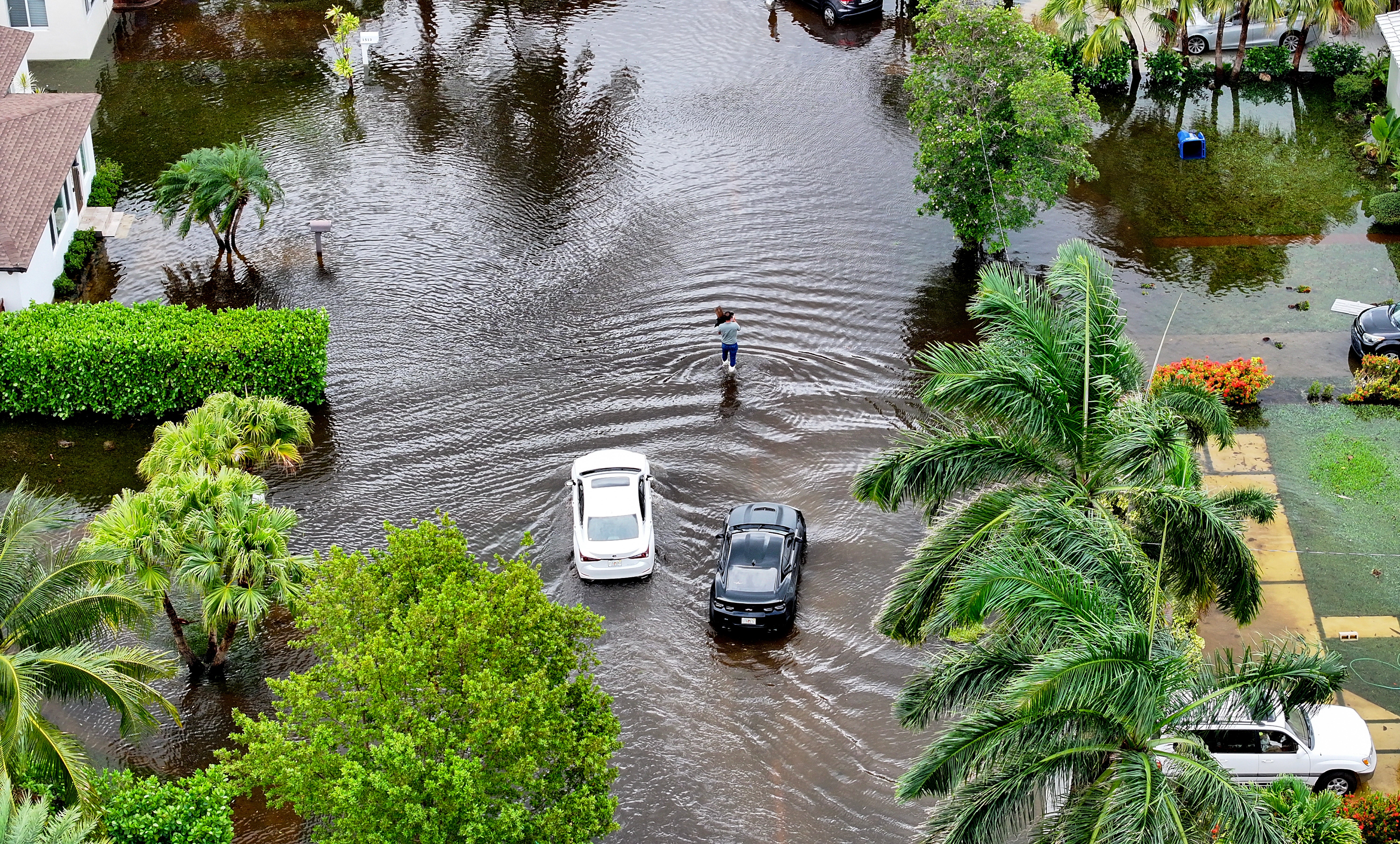 In an aerial view, a person walks through a flooded street on 13 June, 2024, in Hallandale Beach, Florida