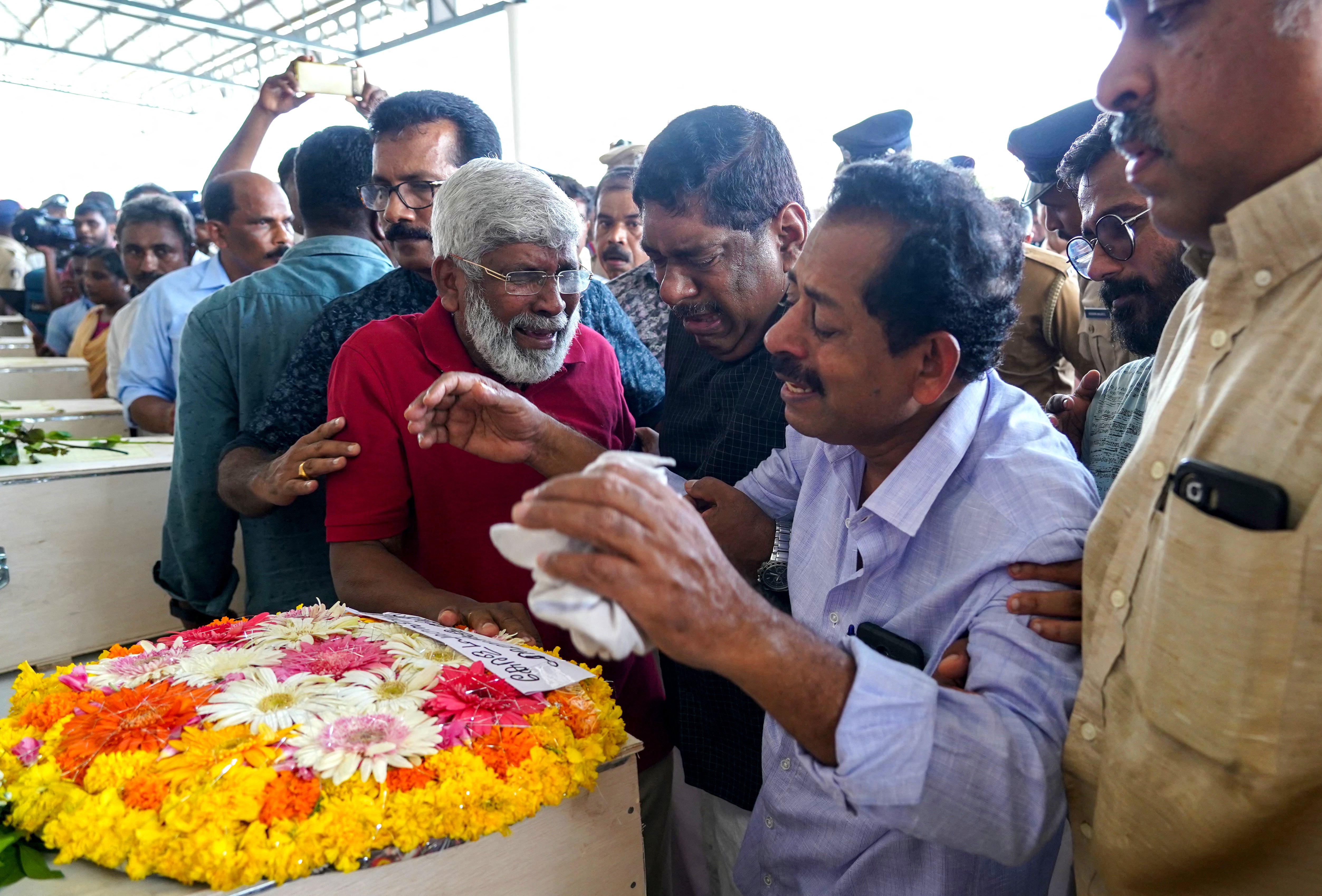 Relatives mourn near the deceased after the coffins' arrival on an Indian Air Force plane from Kuwait