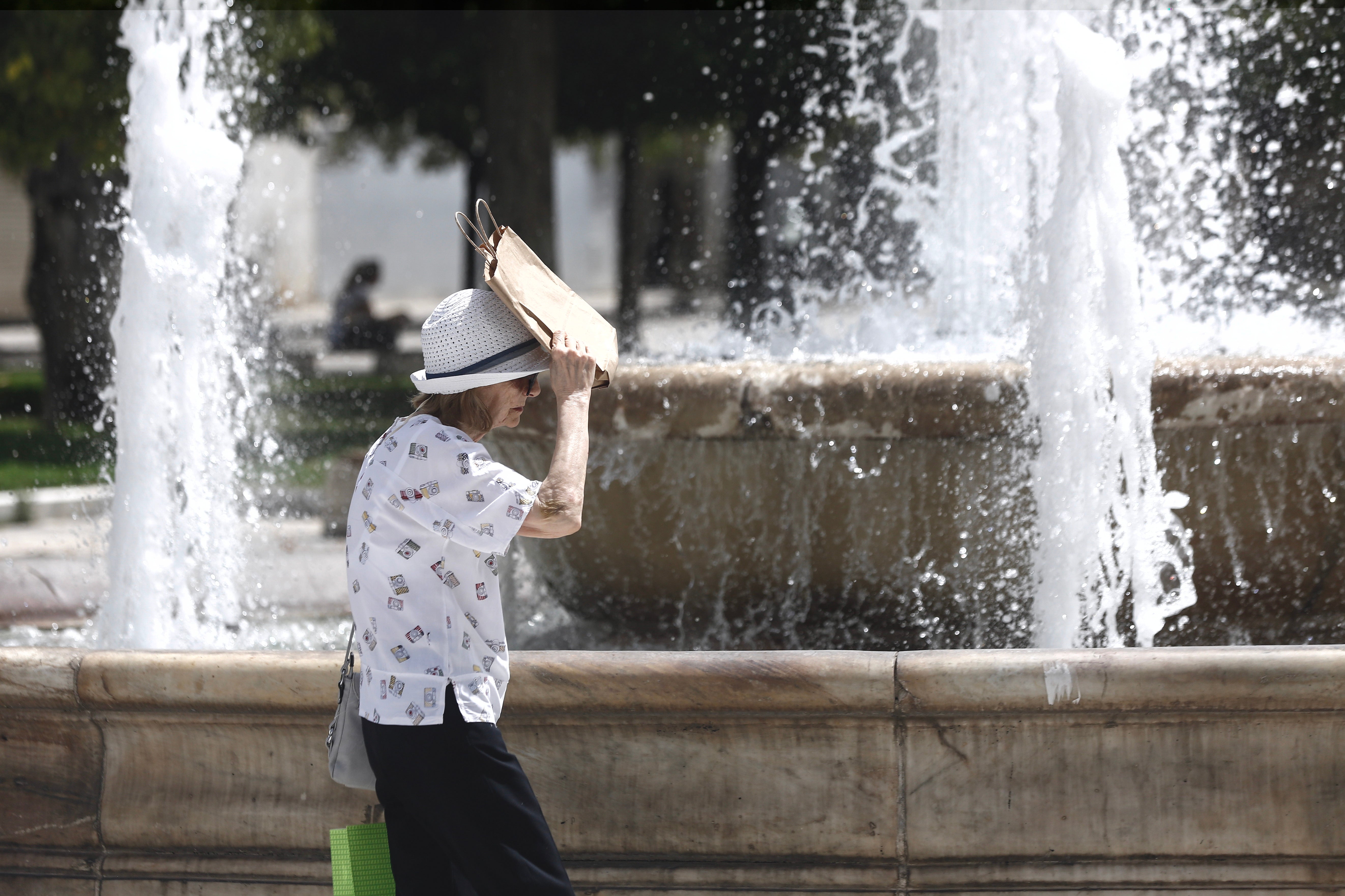 A woman protects herself from the sun while walking in Greece