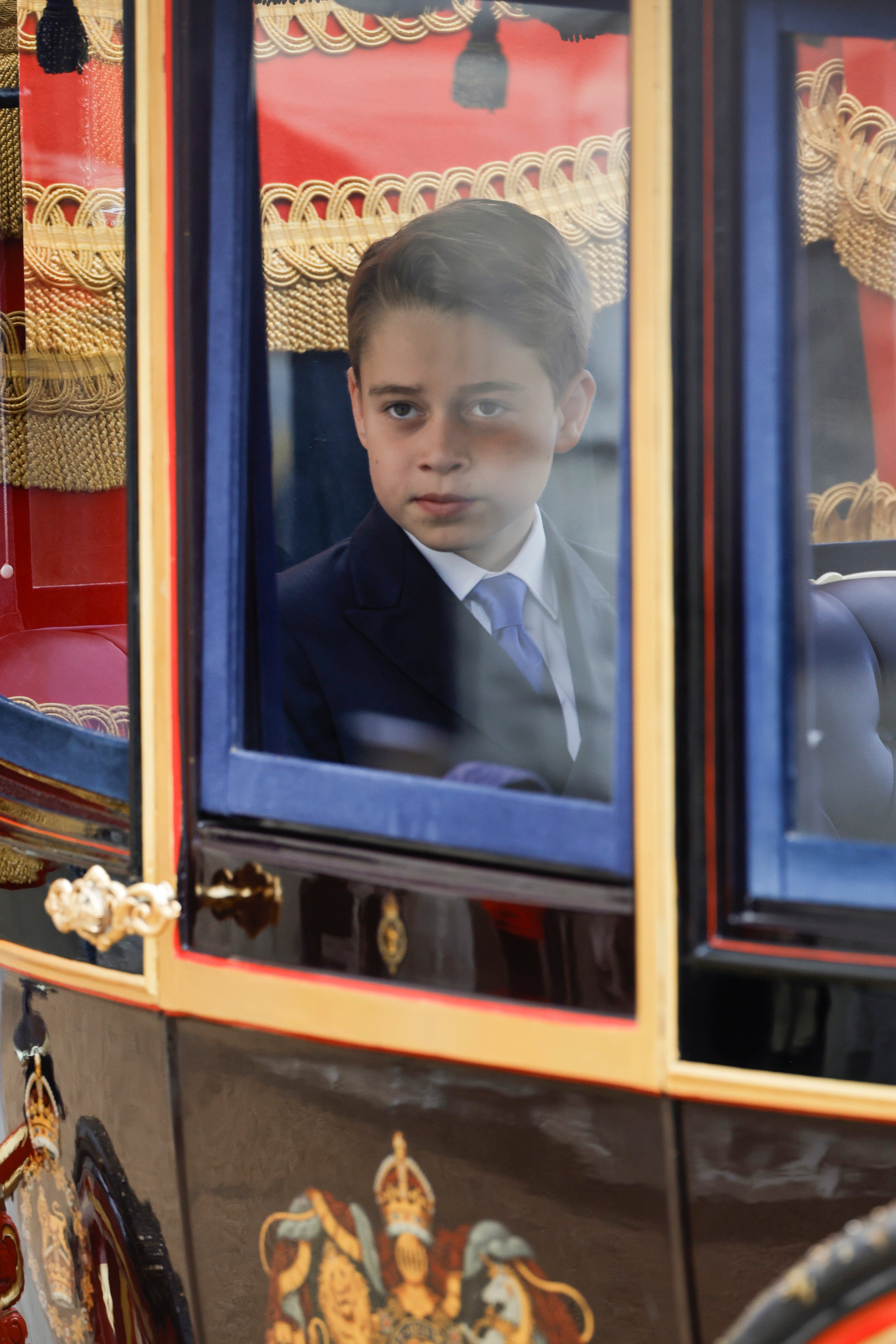 George looks out at the crowd as the carriage proceeds along the route