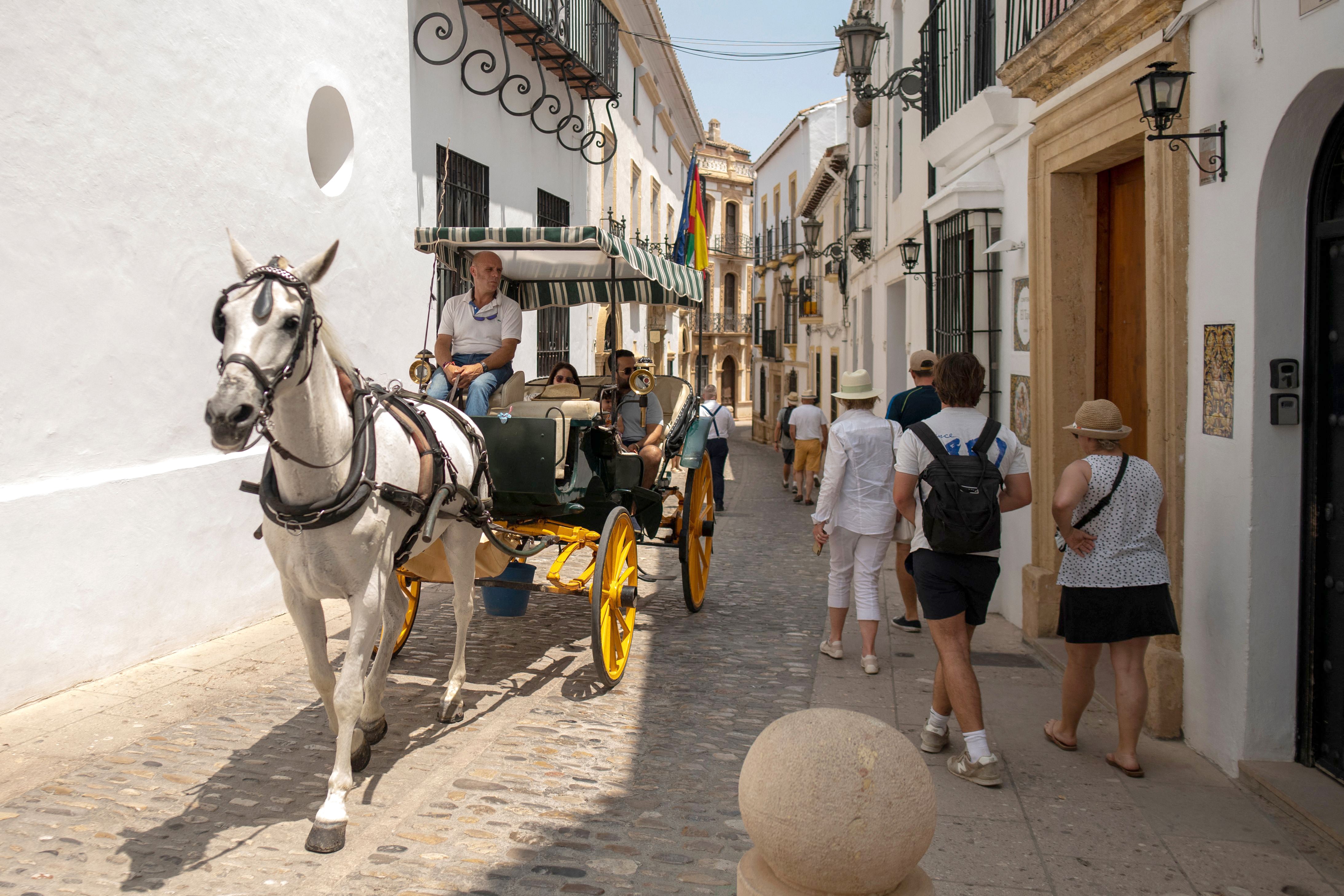 Tourists in Ronda, near Malaga, enjoy a ride in a horse-drawn carriage