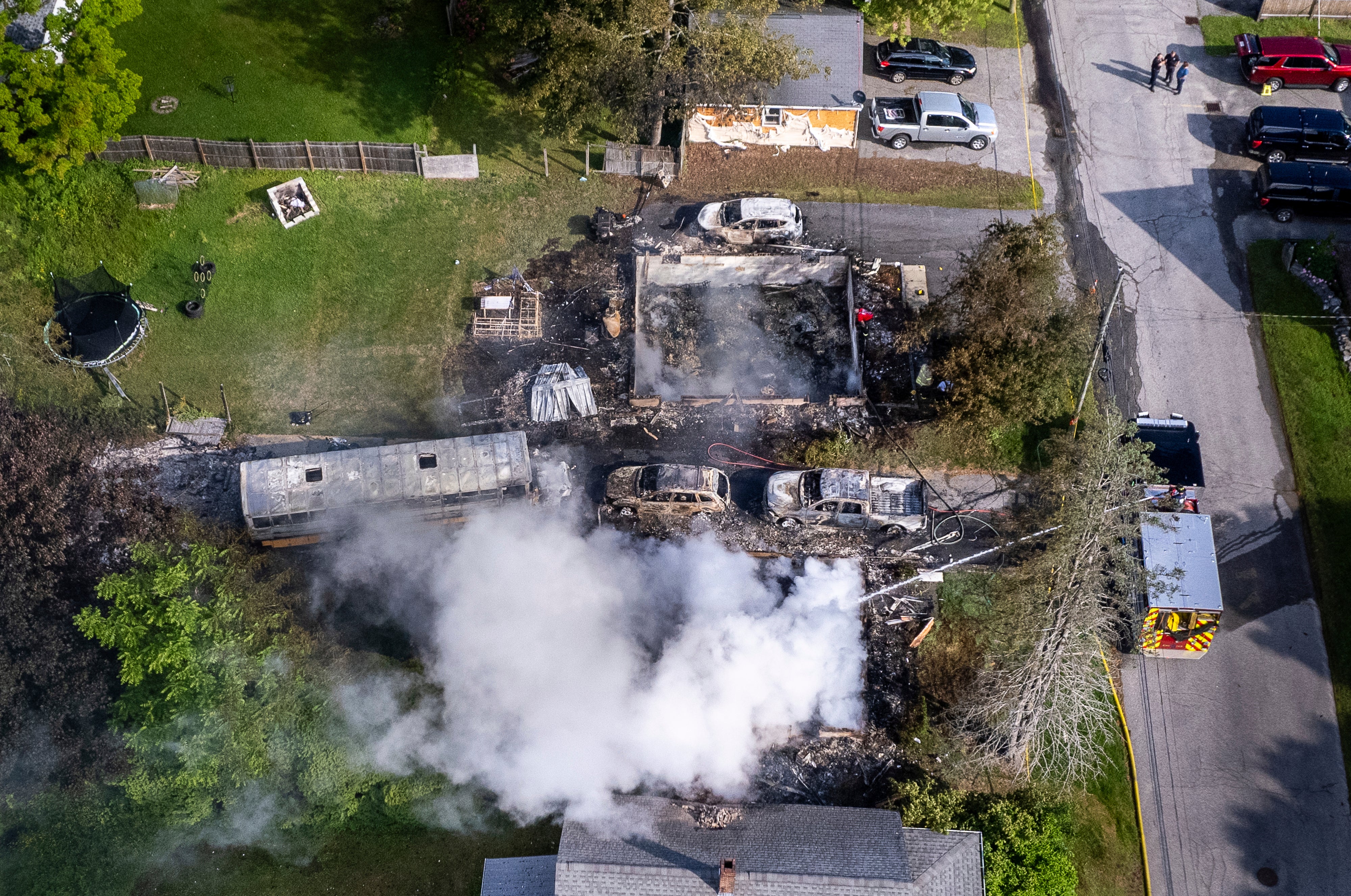 Auburn firefighters hose down the remains of a home in Auburn, Maine, early Saturday after a police shooting. The suspect was recently released on bail