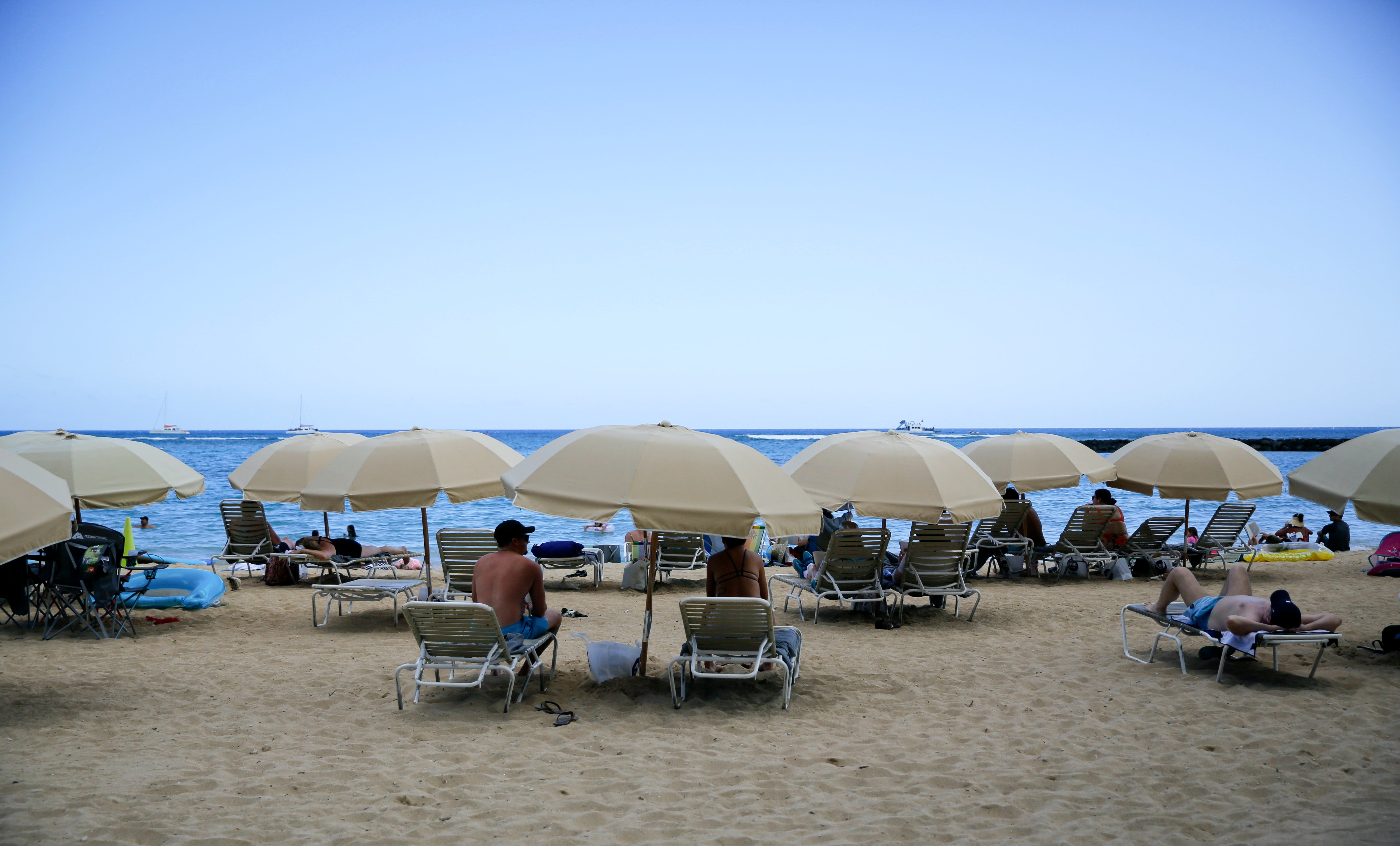 People sit on Waikiki Beach in Honolulu, May 23, 2022