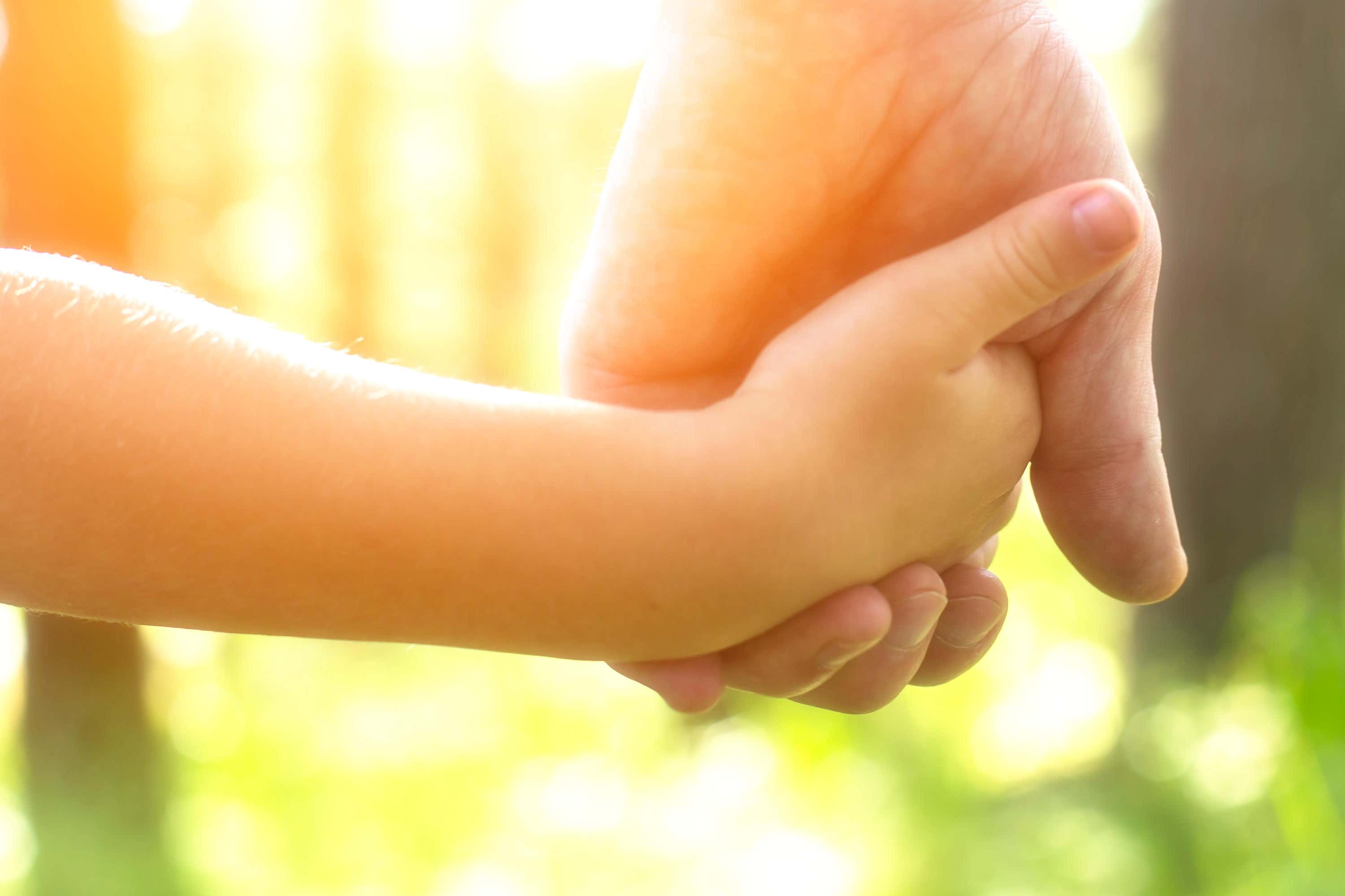 An adult holding a child’s hand (Alamy/PA)