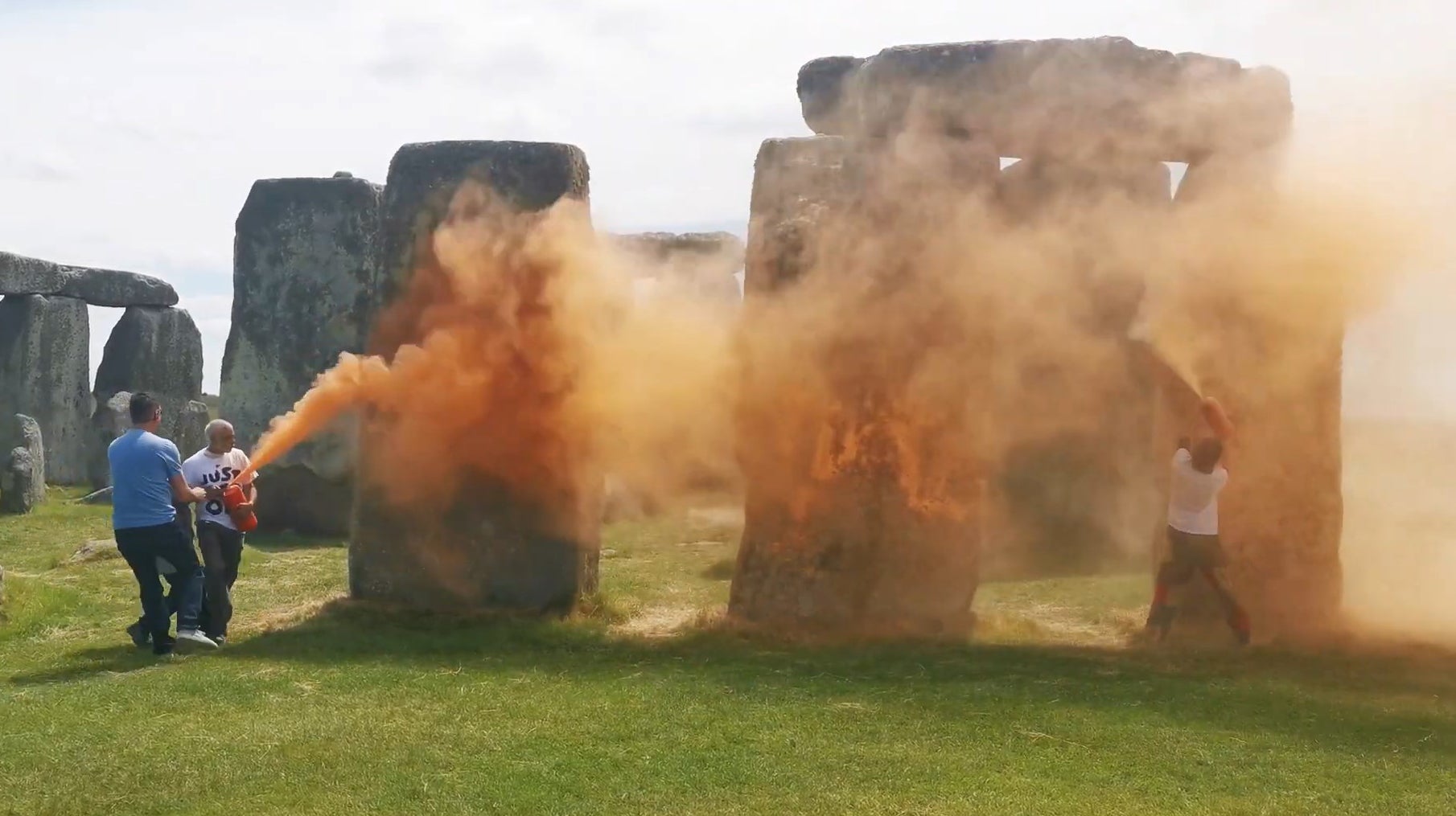 Two people in Just Stop Oil T-shirts, named by the group as Rajan Naidu, 73, and Niamh Lynch, 21, spray the ancient structure with canisters of orange powder paint