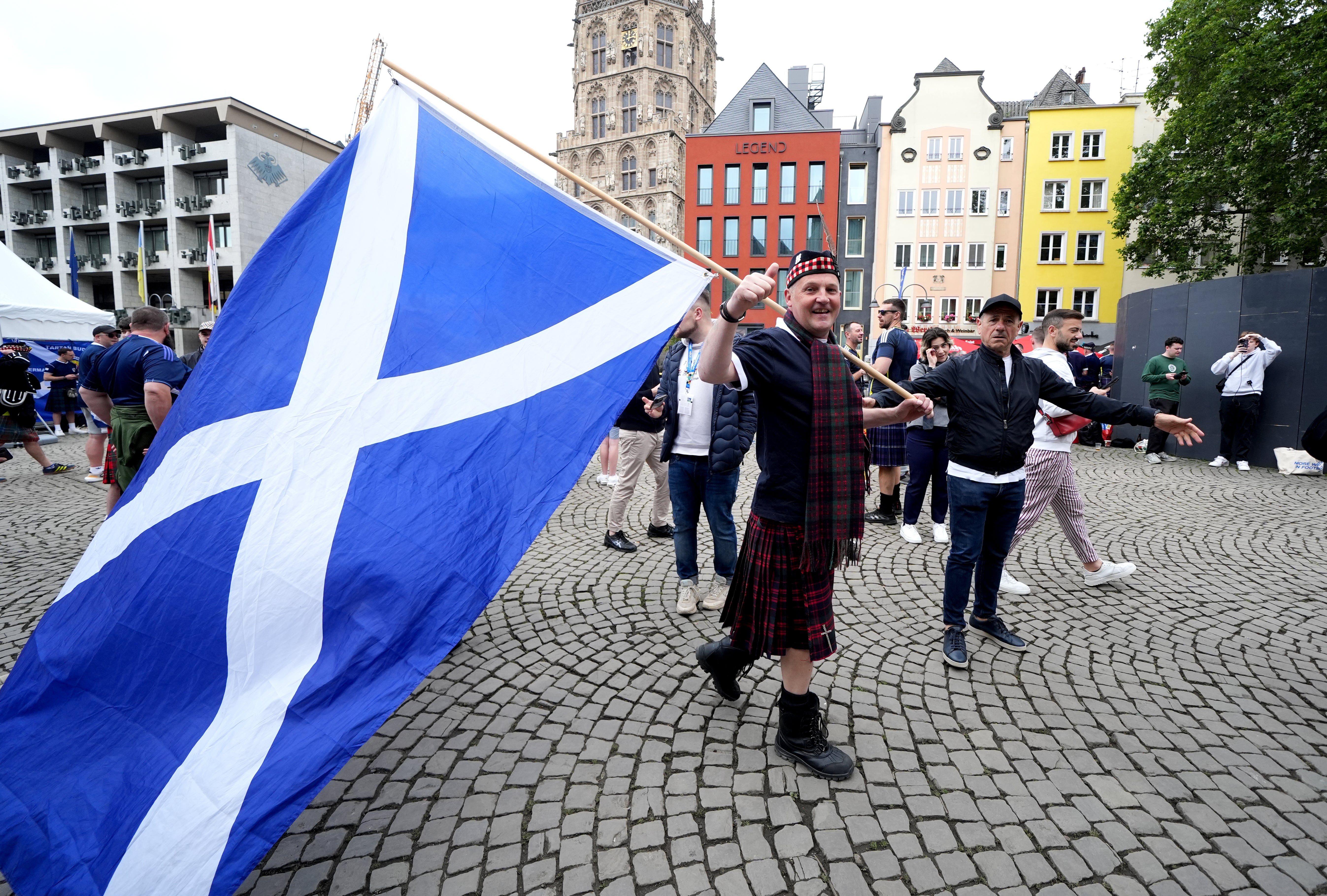 A Scotland fan carries a flag through the Old Market in Cologne, Germany