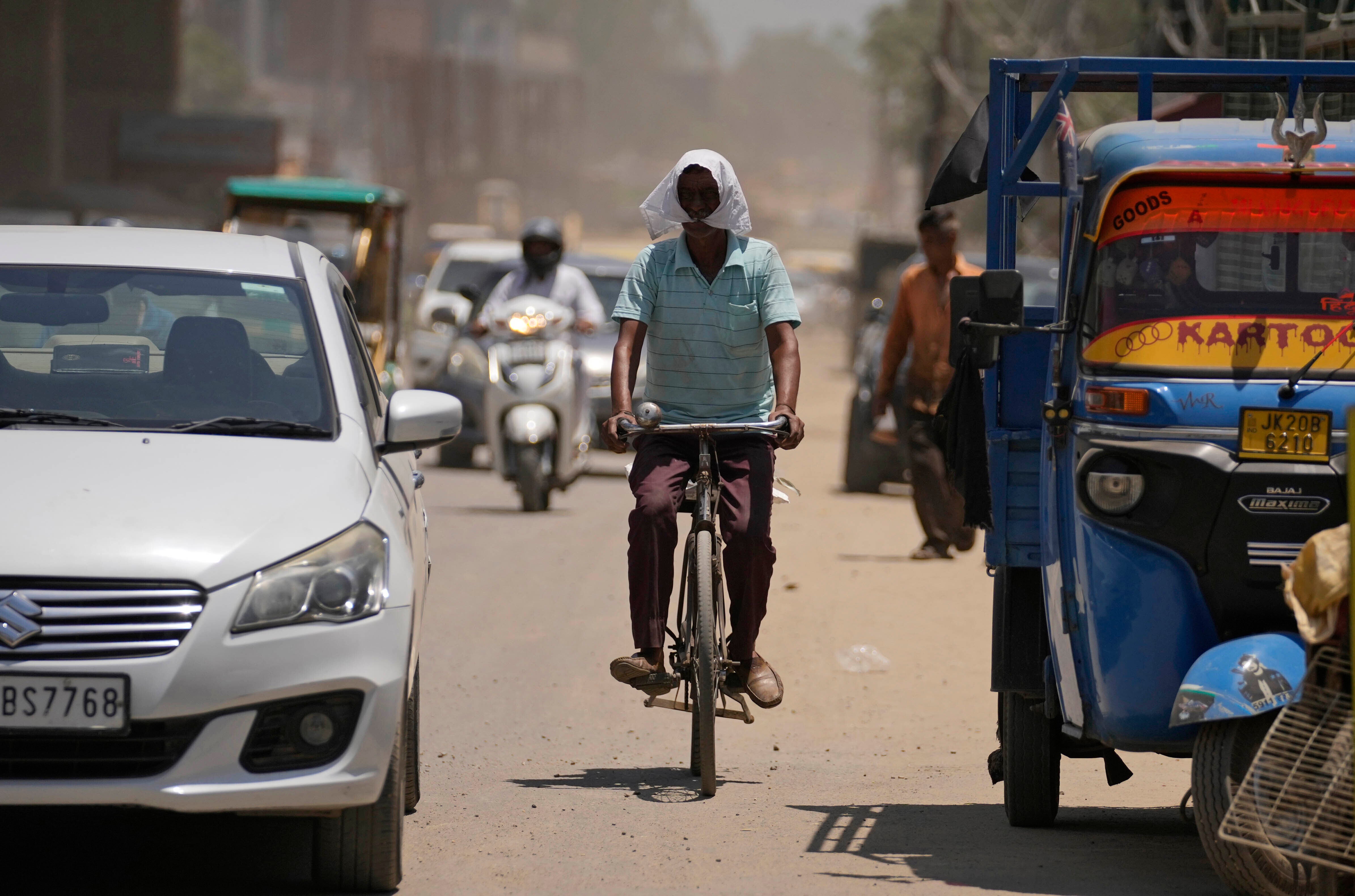 A man covers his face with a cloth to shield from the heat in Jammu, India, in May 2024