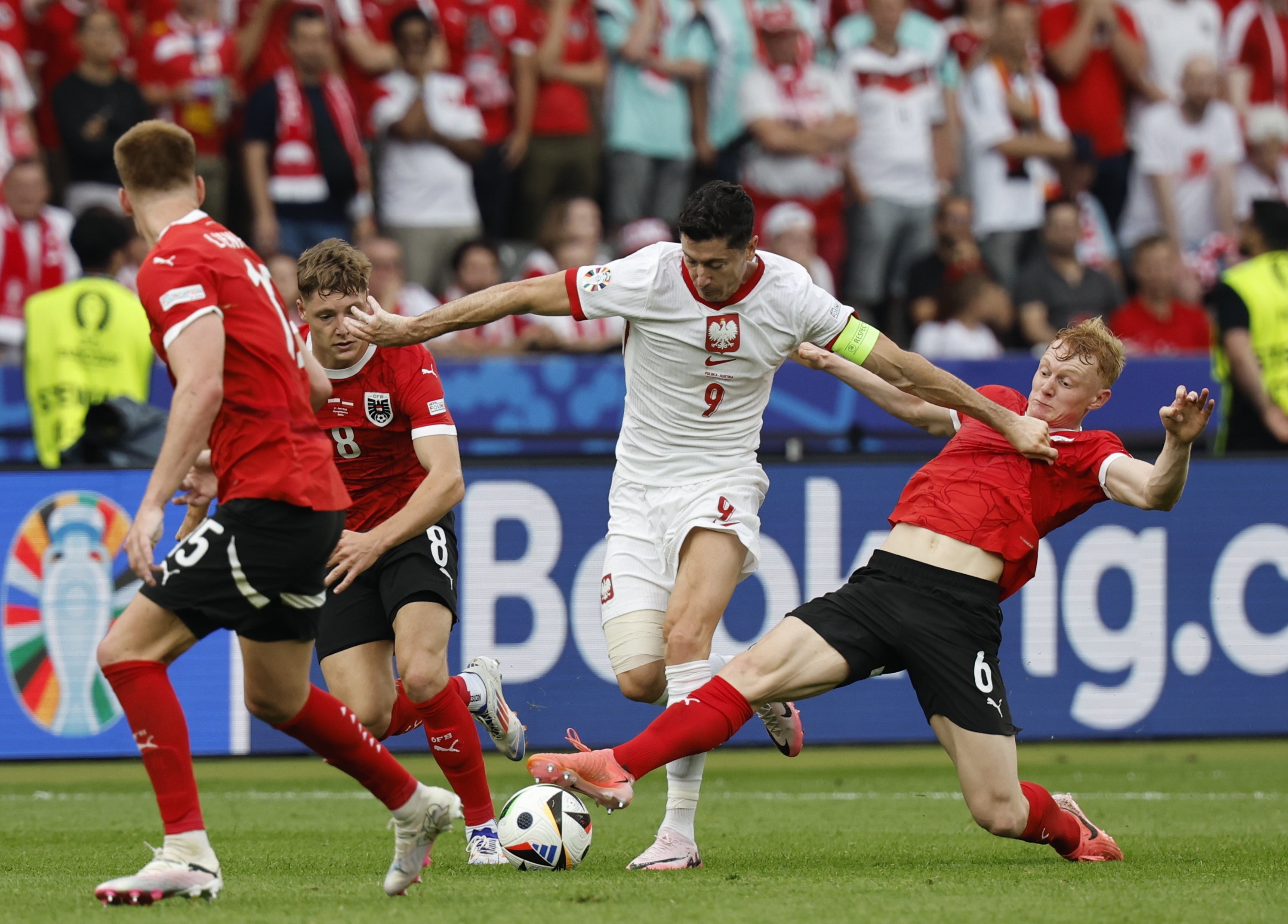 Robert Lewandowski (C) of Poland and Nicolas Seiwald (R) of Austria in action